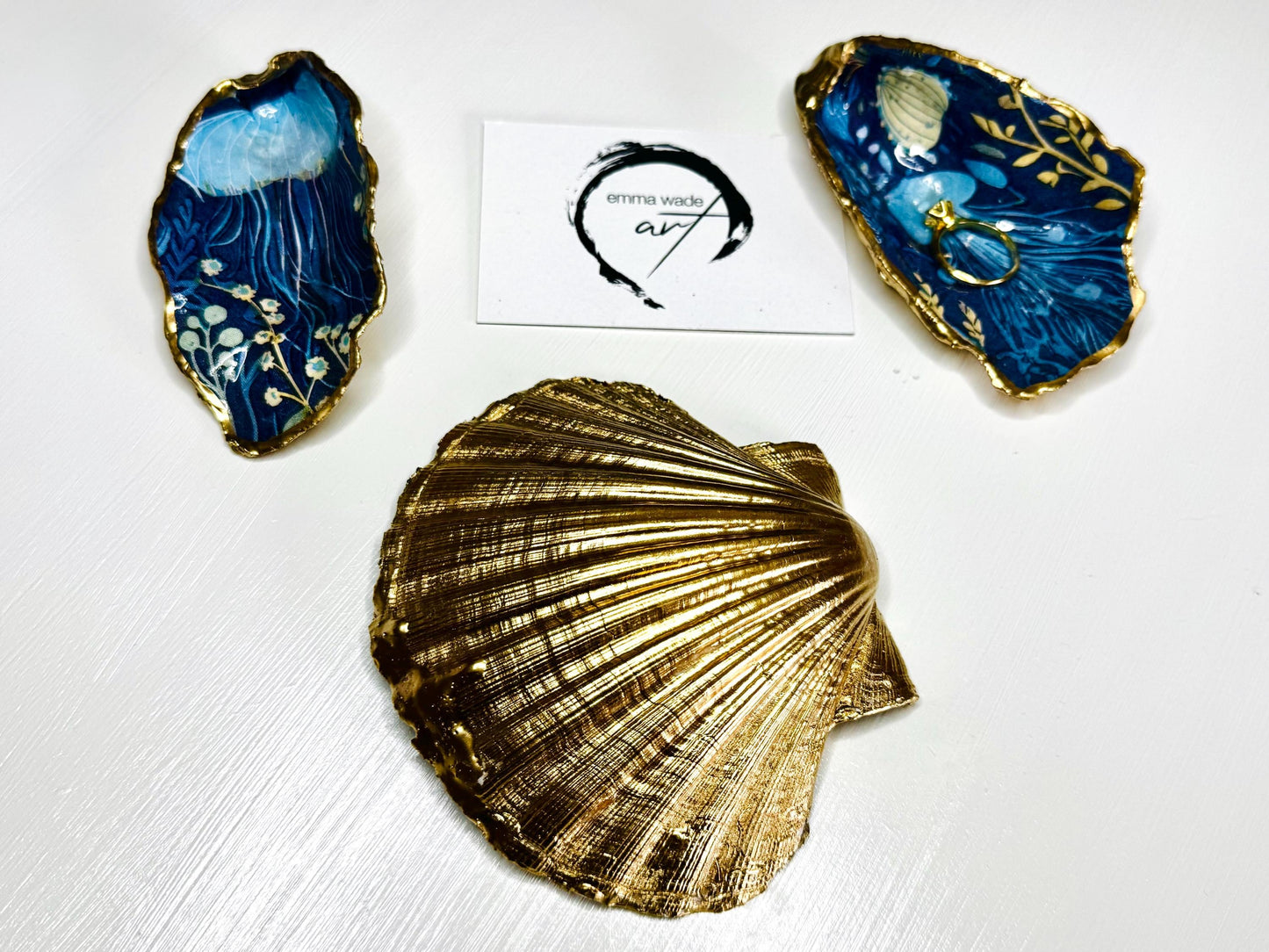 Hand-gilded oyster shell and scallop shell dishes featuring an elegant blue jellyfish design with ocean botanicals, finished with real liquid gold leaf and crystal-clear resin. Coastal ring dishes and jewellery holders available individually or as a matching shell gift set. ✨