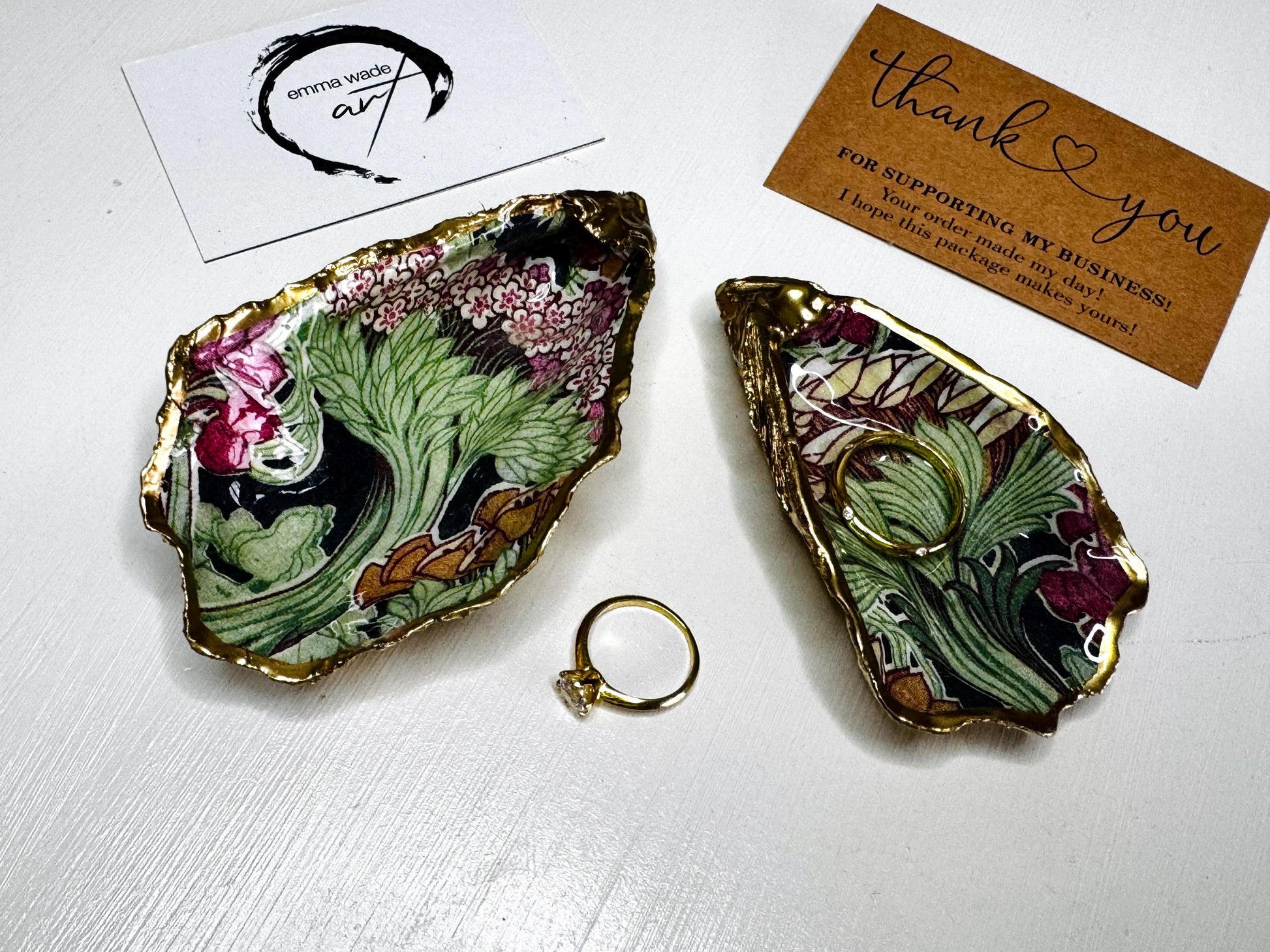 Handcrafted V&A Museum Swirling Trees shell dish collection featuring large and small scallop shells and oyster shells decorated with flowing botanical artwork, pink water lilies and rich green foliage. Each natural Dorset shell is hand-gilded with real liquid gold leaf and sealed with crystal-clear resin. Luxury coastal decor, jewellery dishes, ring holders and trinket trays. Available individually or as a coordinated set of four shells.