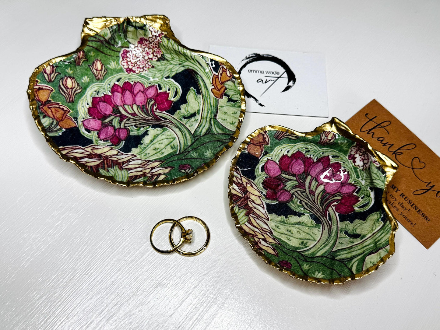 Handcrafted V&A Museum Swirling Trees shell dish collection featuring large and small scallop shells and oyster shells decorated with flowing botanical artwork, pink water lilies and rich green foliage. Each natural Dorset shell is hand-gilded with real liquid gold leaf and sealed with crystal-clear resin. Luxury coastal decor, jewellery dishes, ring holders and trinket trays. Available individually or as a coordinated set of four shells.