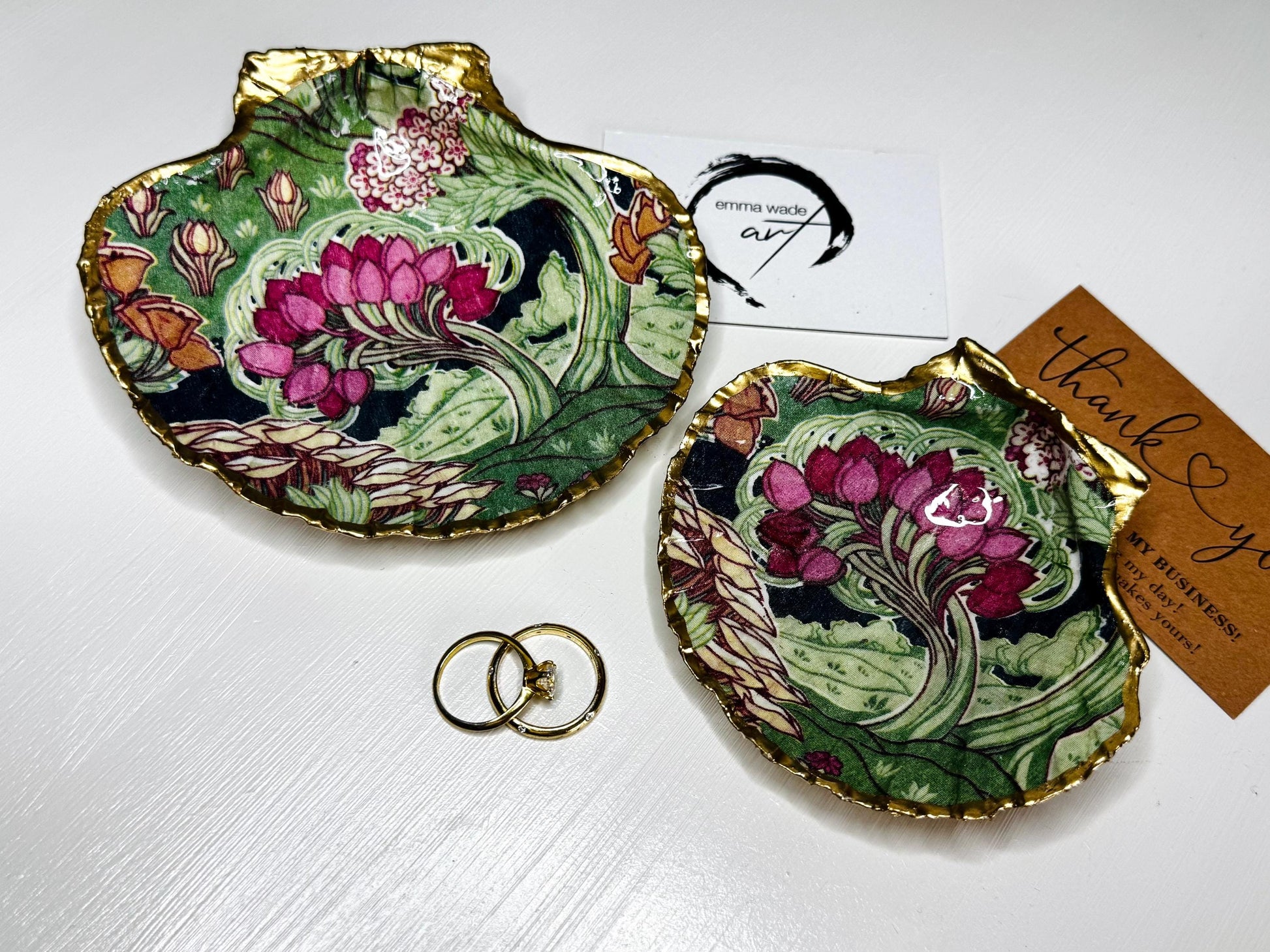 Handcrafted V&A Museum Swirling Trees shell dish collection featuring large and small scallop shells and oyster shells decorated with flowing botanical artwork, pink water lilies and rich green foliage. Each natural Dorset shell is hand-gilded with real liquid gold leaf and sealed with crystal-clear resin. Luxury coastal decor, jewellery dishes, ring holders and trinket trays. Available individually or as a coordinated set of four shells.