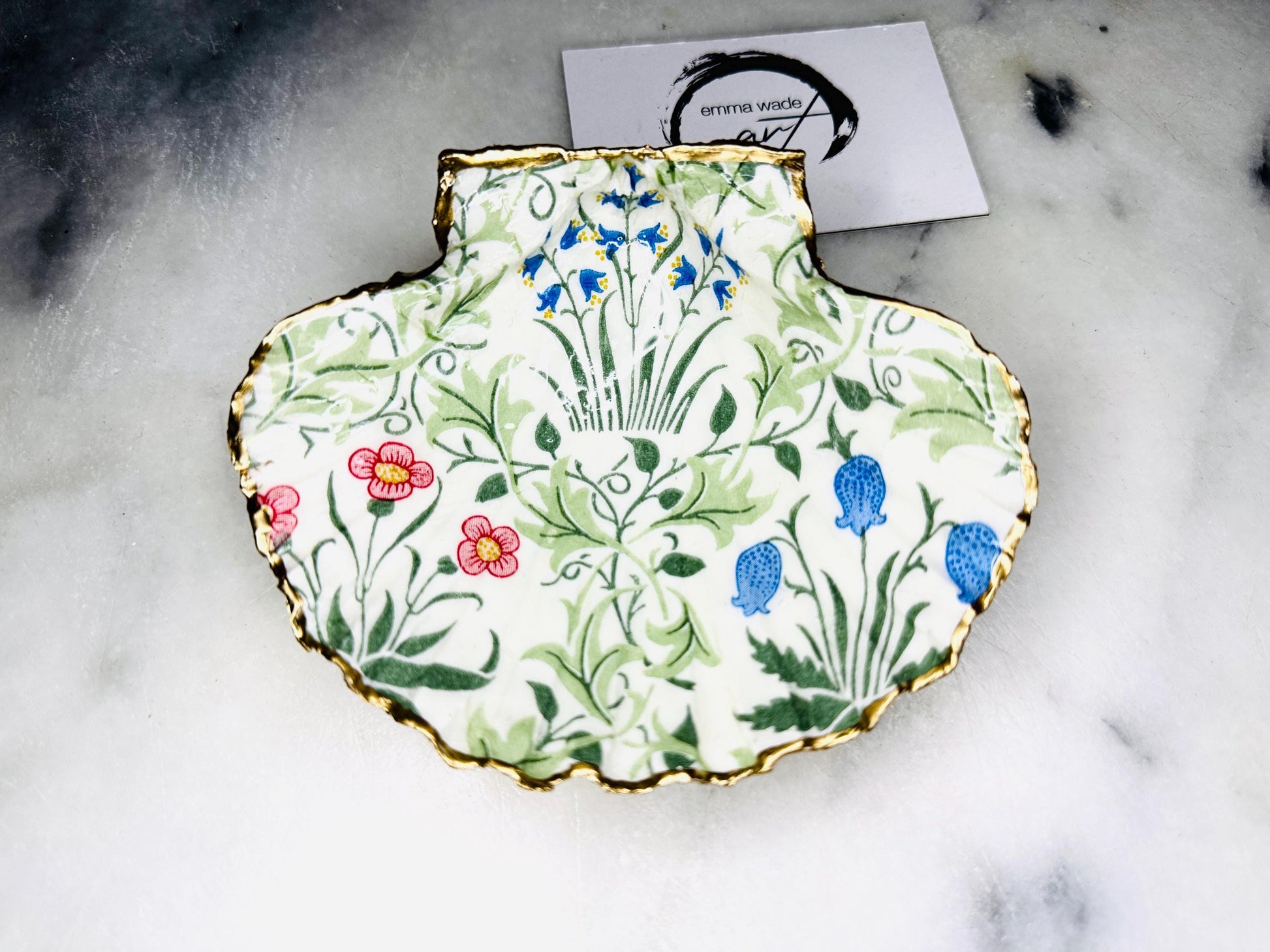 Handcrafted Dorset scallop shell dish featuring William Morris Compton botanical artwork with flowing green foliage and floral details. Natural scallop shell hand-finished with real liquid gold leaf edging and reverse, sealed beneath crystal-clear glossy resin. Luxury jewellery dish, ring holder and trinket tray for coastal, cottagecore and Arts & Crafts inspired interiors. Available in small and large scallop shell sizes.