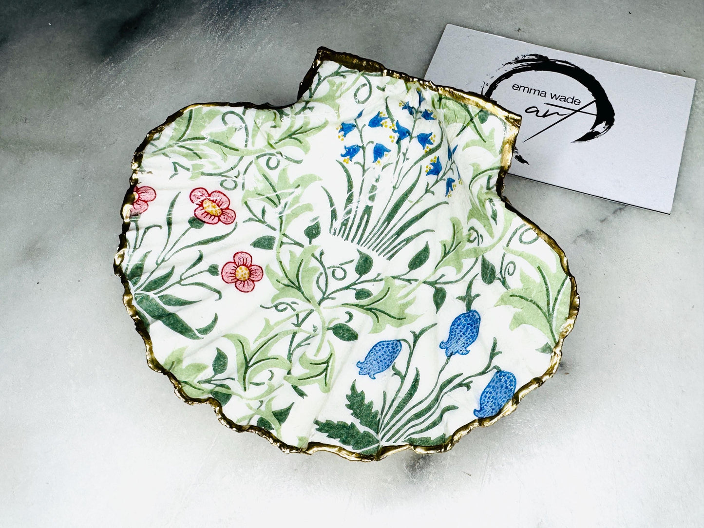 Handcrafted Dorset scallop shell dish featuring William Morris Compton botanical artwork with flowing green foliage and floral details. Natural scallop shell hand-finished with real liquid gold leaf edging and reverse, sealed beneath crystal-clear glossy resin. Luxury jewellery dish, ring holder and trinket tray for coastal, cottagecore and Arts & Crafts inspired interiors. Available in small and large scallop shell sizes.