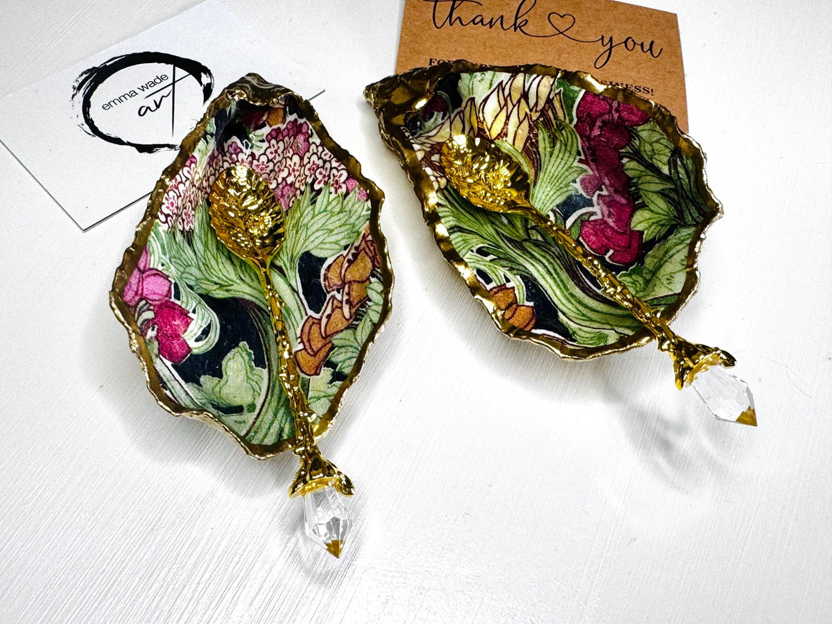 Handcrafted pair of oyster shell salt and pepper pinch pots featuring the Forest Trees botanical design in rich green, pink, cream and gold tones. Natural Dorset oyster shells hand-finished with liquid gold leaf edging and sealed beneath a crystal-clear resin for a glossy finish. Includes optional gold crystal spoons. Elegant table decor for dining, entertaining, weddings, anniversaries and housewarming gifts. Handmade in Surrey, England by Emma Wade ART.