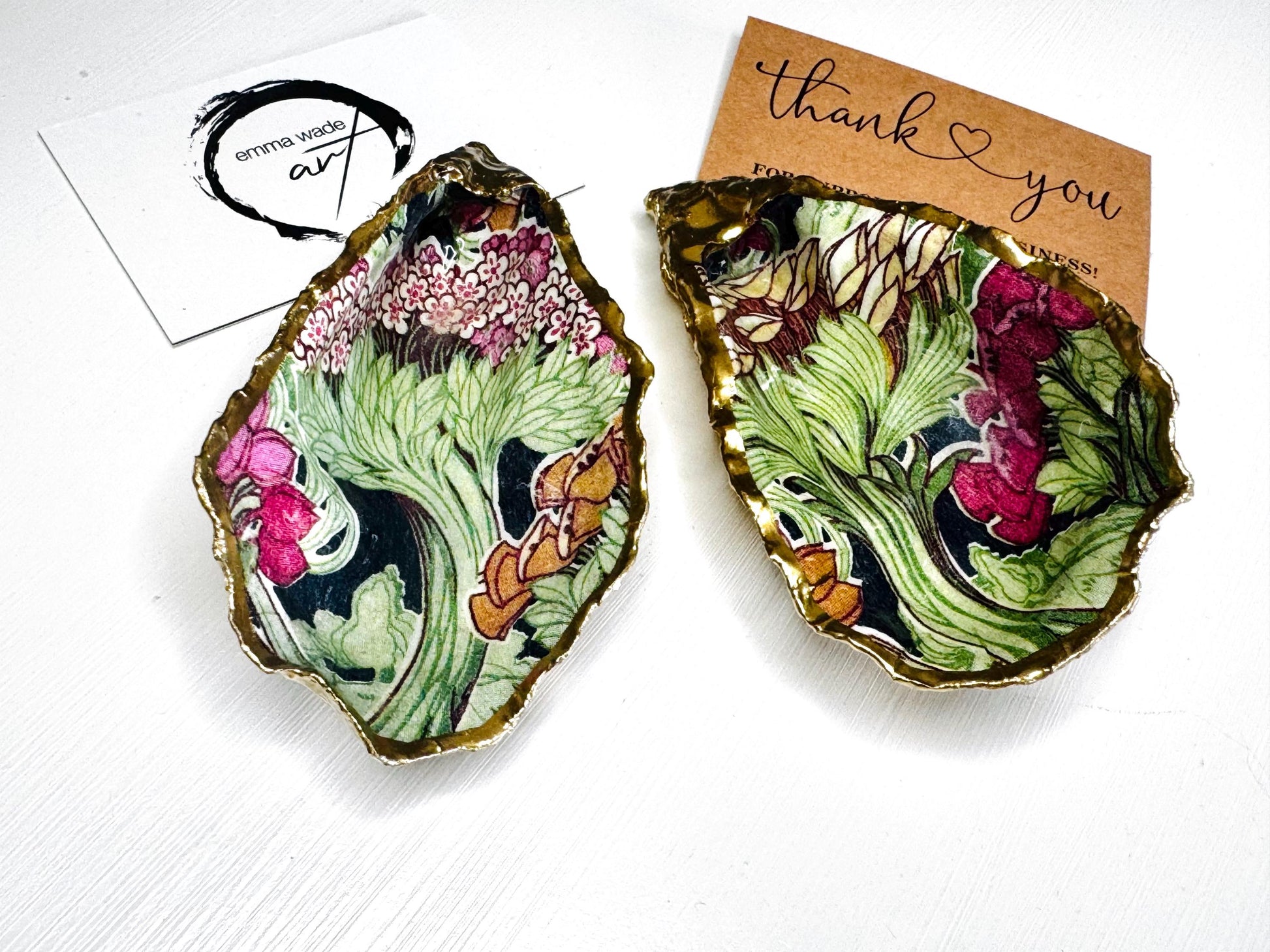 Handcrafted pair of oyster shell salt and pepper pinch pots featuring the Forest Trees botanical design in rich green, pink, cream and gold tones. Natural Dorset oyster shells hand-finished with liquid gold leaf edging and sealed beneath a crystal-clear resin for a glossy finish. Includes optional gold crystal spoons. Elegant table decor for dining, entertaining, weddings, anniversaries and housewarming gifts. Handmade in Surrey, England by Emma Wade ART.
