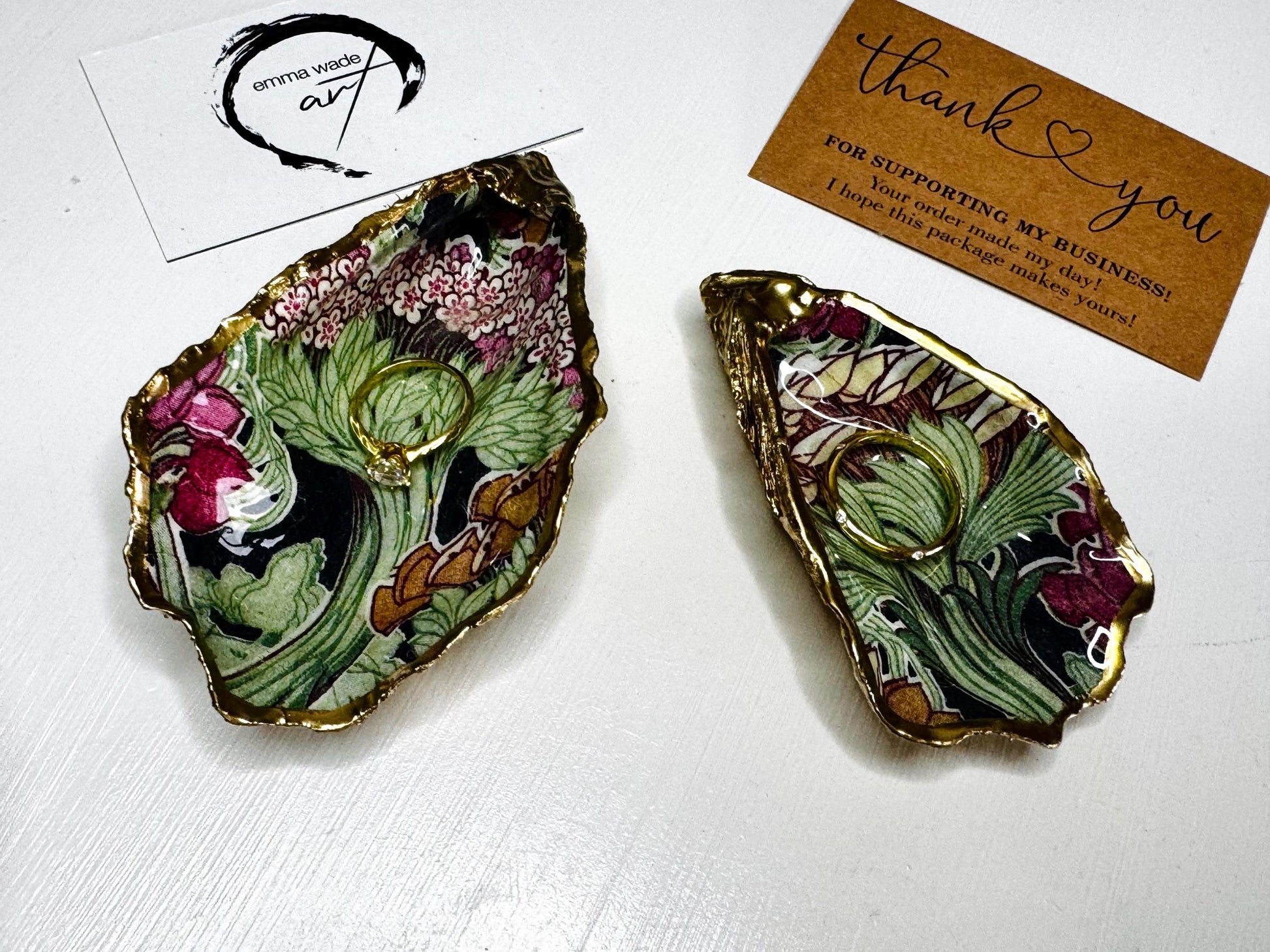 Handcrafted V&A Museum Swirling Trees shell dish collection featuring large and small scallop shells and oyster shells decorated with flowing botanical artwork, pink water lilies and rich green foliage. Each natural Dorset shell is hand-gilded with real liquid gold leaf and sealed with crystal-clear resin. Luxury coastal decor, jewellery dishes, ring holders and trinket trays. Available individually or as a coordinated set of four shells.