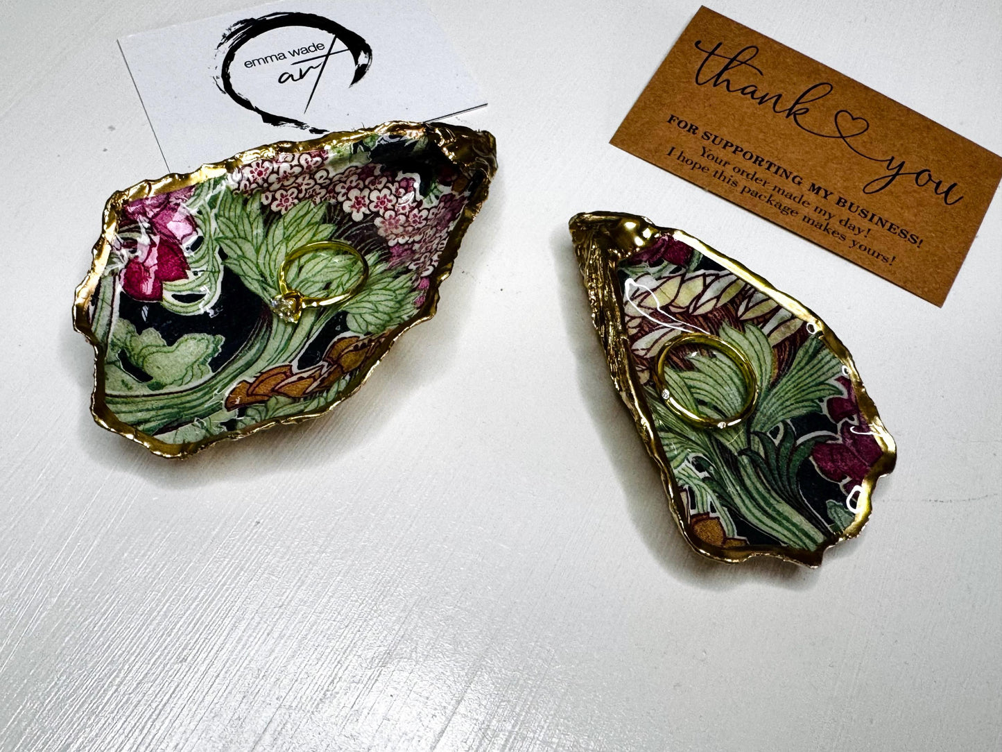 Handcrafted V&A Museum Swirling Trees shell dish collection featuring large and small scallop shells and oyster shells decorated with flowing botanical artwork, pink water lilies and rich green foliage. Each natural Dorset shell is hand-gilded with real liquid gold leaf and sealed with crystal-clear resin. Luxury coastal decor, jewellery dishes, ring holders and trinket trays. Available individually or as a coordinated set of four shells.