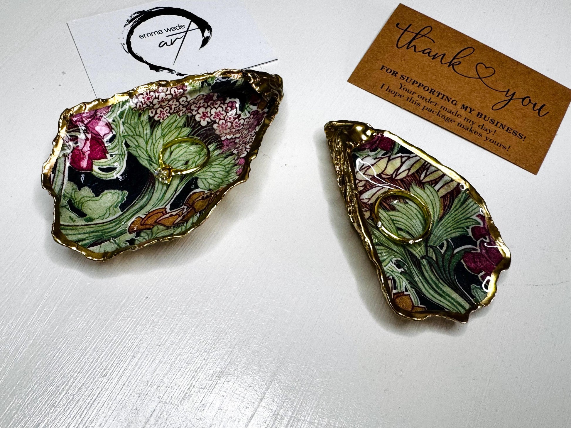 Handcrafted V&A Museum Swirling Trees shell dish collection featuring large and small scallop shells and oyster shells decorated with flowing botanical artwork, pink water lilies and rich green foliage. Each natural Dorset shell is hand-gilded with real liquid gold leaf and sealed with crystal-clear resin. Luxury coastal decor, jewellery dishes, ring holders and trinket trays. Available individually or as a coordinated set of four shells.