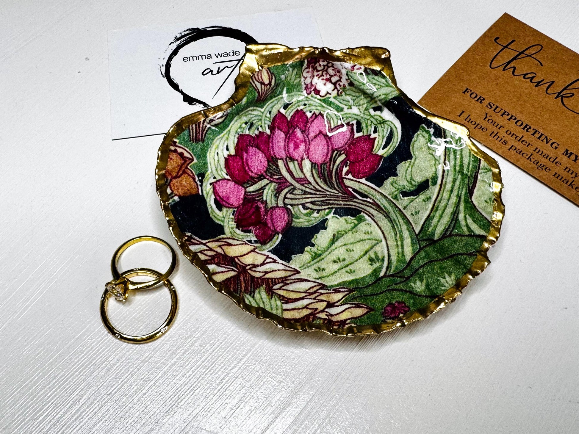 Handcrafted V&A Museum Swirling Trees shell dish collection featuring large and small scallop shells and oyster shells decorated with flowing botanical artwork, pink water lilies and rich green foliage. Each natural Dorset shell is hand-gilded with real liquid gold leaf and sealed with crystal-clear resin. Luxury coastal decor, jewellery dishes, ring holders and trinket trays. Available individually or as a coordinated set of four shells.