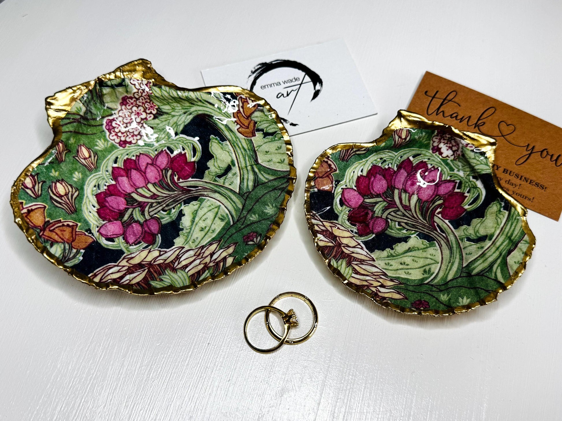 Handcrafted V&A Museum Swirling Trees shell dish collection featuring large and small scallop shells and oyster shells decorated with flowing botanical artwork, pink water lilies and rich green foliage. Each natural Dorset shell is hand-gilded with real liquid gold leaf and sealed with crystal-clear resin. Luxury coastal decor, jewellery dishes, ring holders and trinket trays. Available individually or as a coordinated set of four shells.