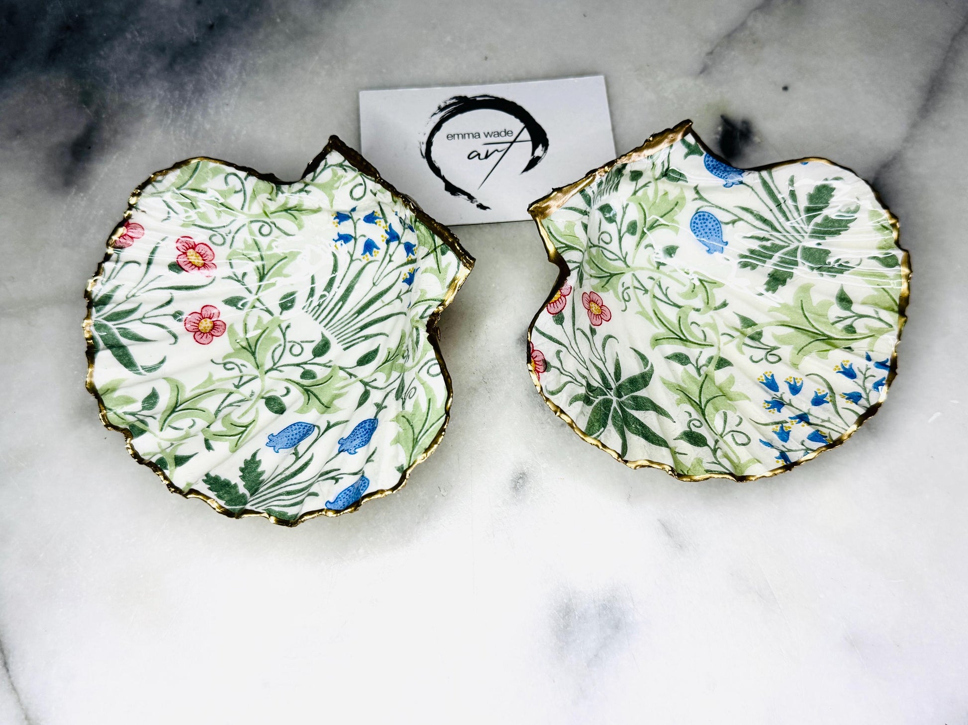 Handcrafted Dorset scallop shell dish featuring William Morris Compton botanical artwork with flowing green foliage and floral details. Natural scallop shell hand-finished with real liquid gold leaf edging and reverse, sealed beneath crystal-clear glossy resin. Luxury jewellery dish, ring holder and trinket tray for coastal, cottagecore and Arts & Crafts inspired interiors. Available in small and large scallop shell sizes.