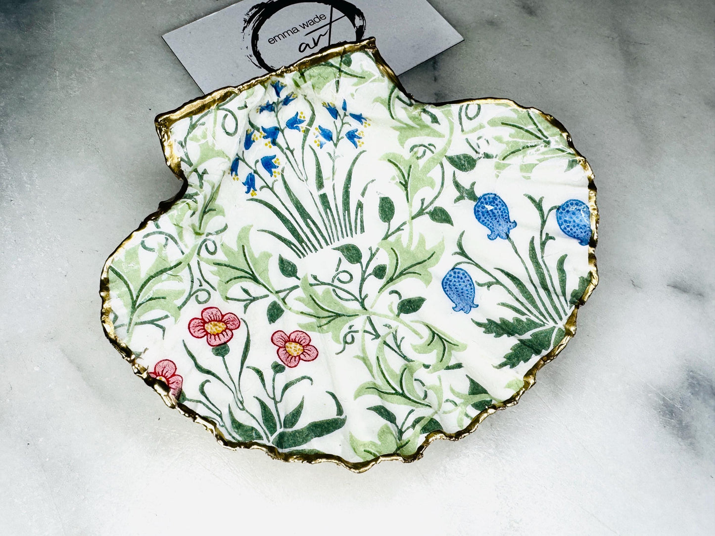 Handcrafted Dorset scallop shell dish featuring William Morris Compton botanical artwork with flowing green foliage and floral details. Natural scallop shell hand-finished with real liquid gold leaf edging and reverse, sealed beneath crystal-clear glossy resin. Luxury jewellery dish, ring holder and trinket tray for coastal, cottagecore and Arts & Crafts inspired interiors. Available in small and large scallop shell sizes.
