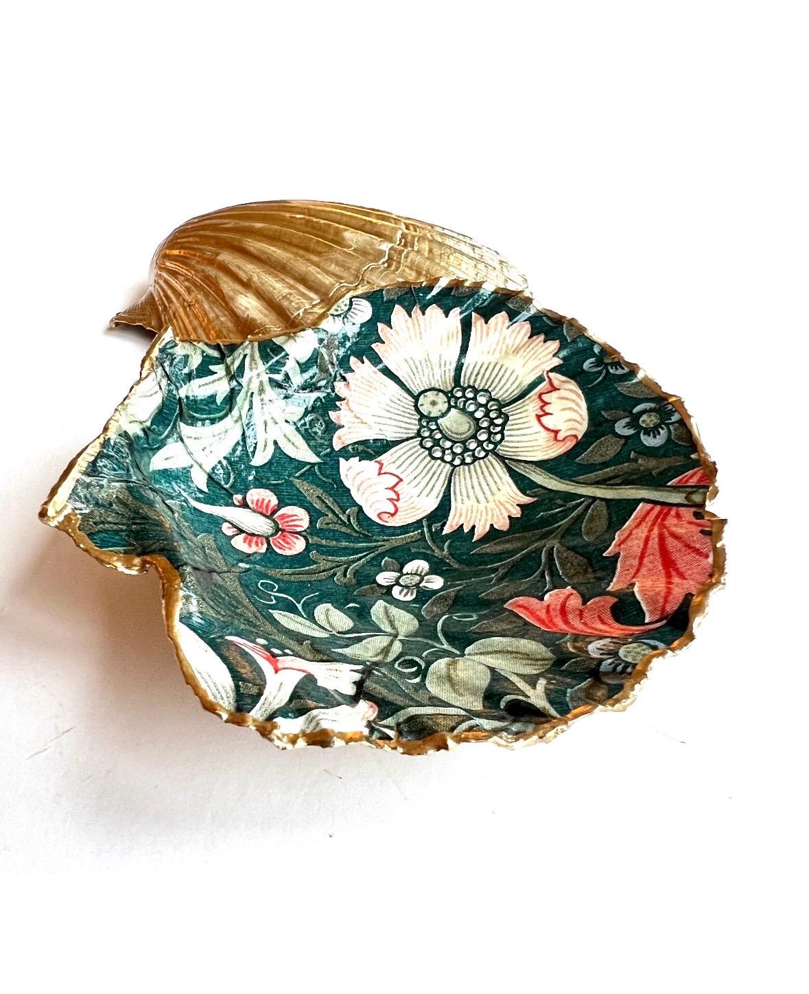 William Morris Compton dark blue scallop shell dish hand finished with liquid gold leaf and sealed with crystal-clear gloss resin. Natural Dorset shell decorated with botanical floral design in blue, green and cream. Available in small 10–11cm or large 12–14cm. Ideal as a jewellery dish, ring holder, trinket tray, cufflink dish, tea light holder or coastal home decor gift.