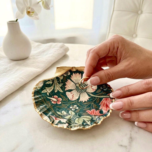 William Morris Compton dark blue scallop shell dish hand finished with liquid gold leaf and sealed with crystal-clear gloss resin. Natural Dorset shell decorated with botanical floral design in blue, green and cream. Available in small 10–11cm or large 12–14cm. Ideal as a jewellery dish, ring holder, trinket tray, cufflink dish, tea light holder or coastal home decor gift.