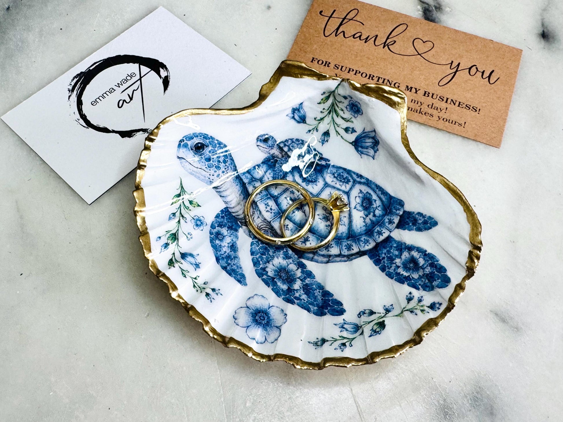 Sea Turtle Mum and Baby scallop shell trinket dish featuring an original illustrated Delft Blue design by Emma Wade ART. Natural scallop shell finished with gold leaf or silver leaf edging and a crystal-clear glossy resin coating. Coastal jewellery tray, ring holder and ocean-inspired gift for sea turtle lovers, beach house décor, weddings, bridesmaids and nautical homes.