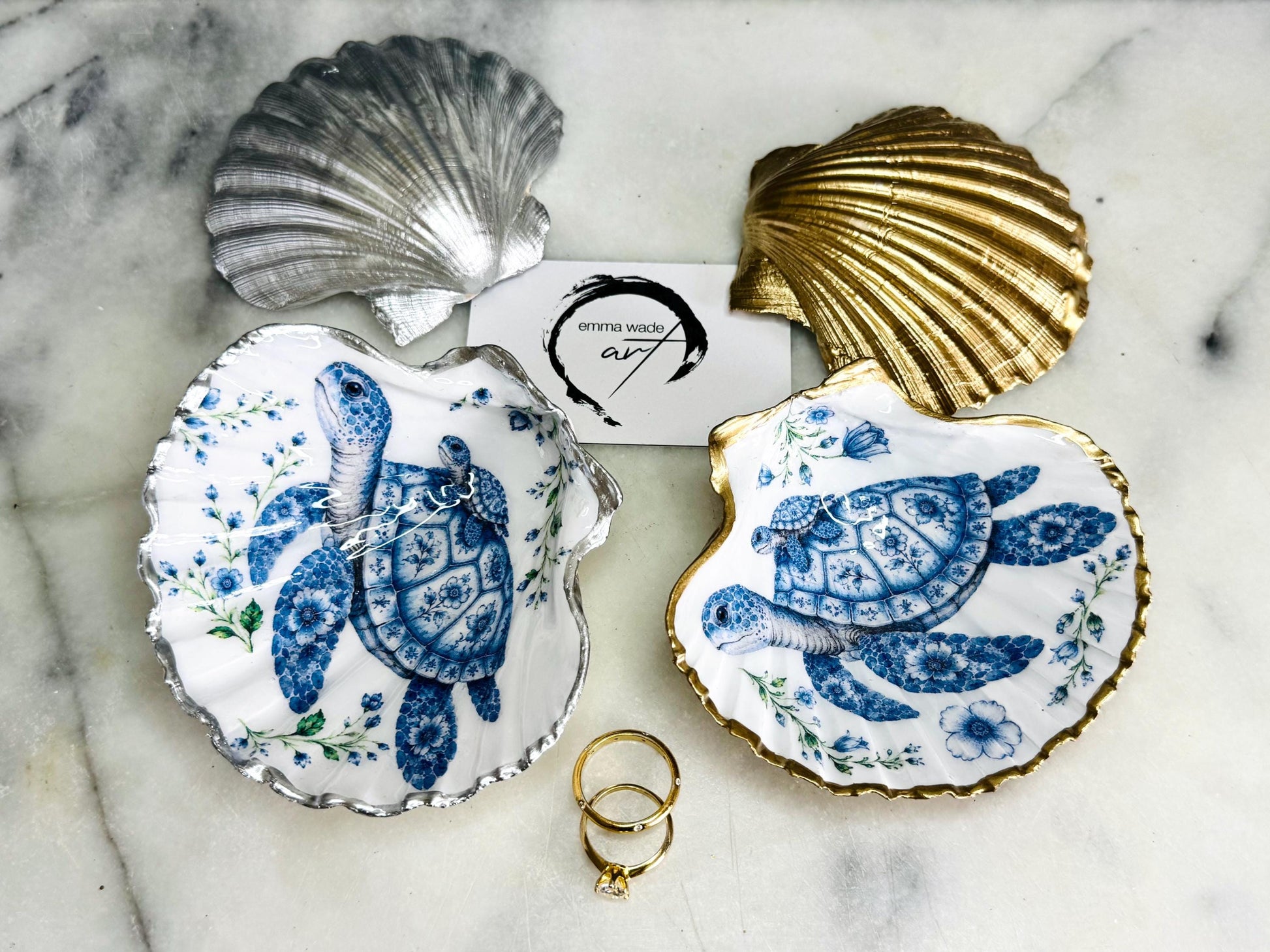 Sea Turtle Mum and Baby scallop shell trinket dish featuring an original illustrated Delft Blue design by Emma Wade ART. Natural scallop shell finished with gold leaf or silver leaf edging and a crystal-clear glossy resin coating. Coastal jewellery tray, ring holder and ocean-inspired gift for sea turtle lovers, beach house décor, weddings, bridesmaids and nautical homes.