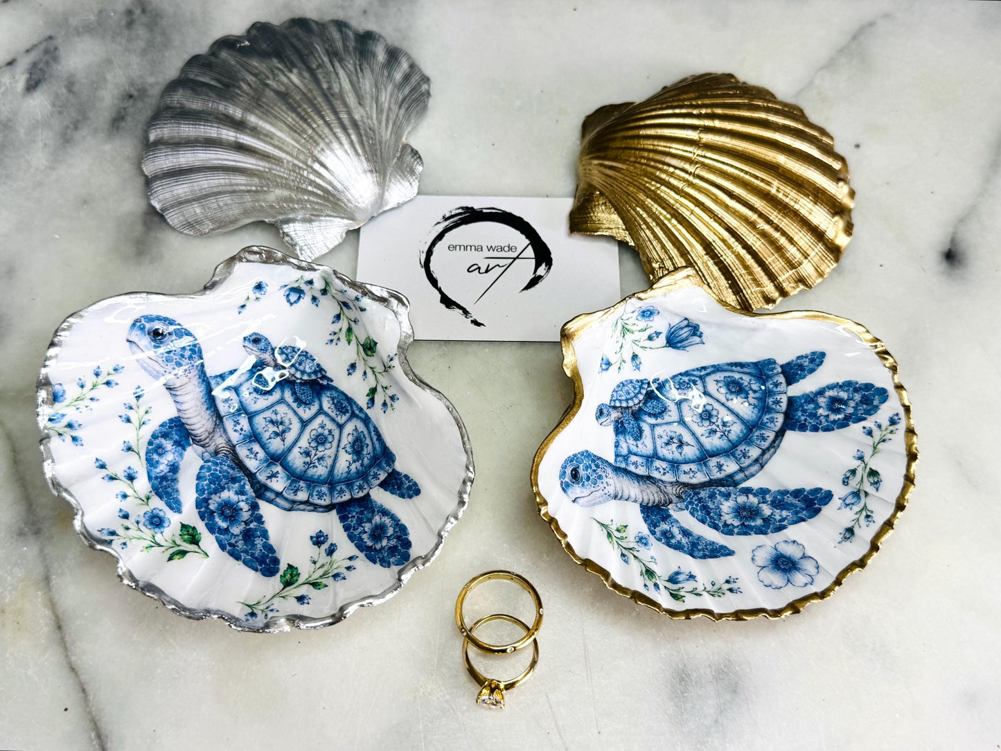 Sea Turtle Mum and Baby scallop shell trinket dish featuring an original illustrated Delft Blue design by Emma Wade ART. Natural scallop shell finished with gold leaf or silver leaf edging and a crystal-clear glossy resin coating. Coastal jewellery tray, ring holder and ocean-inspired gift for sea turtle lovers, beach house décor, weddings, bridesmaids and nautical homes.