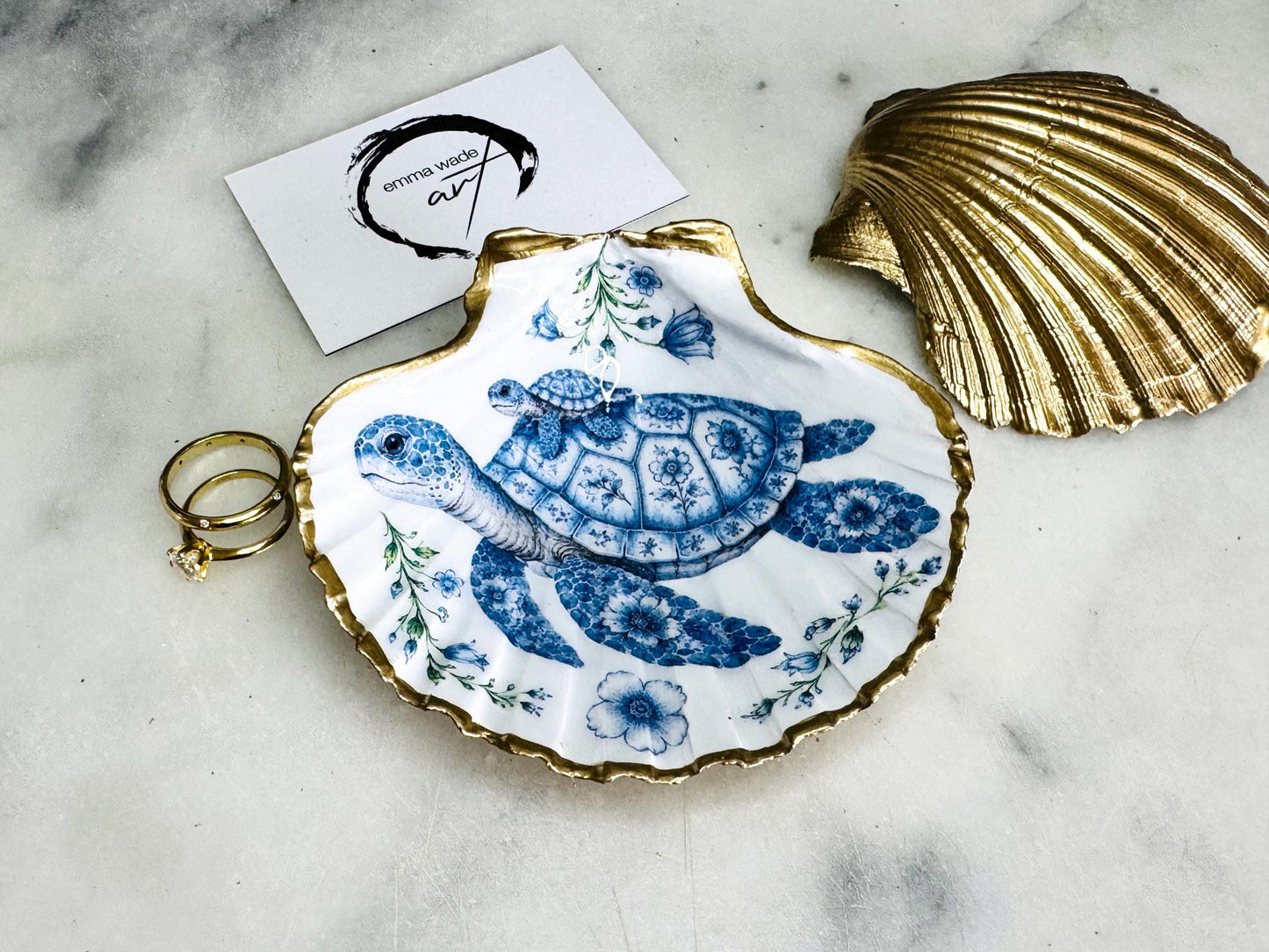 Sea Turtle Mum and Baby scallop shell trinket dish featuring an original illustrated Delft Blue design by Emma Wade ART. Natural scallop shell finished with gold leaf or silver leaf edging and a crystal-clear glossy resin coating. Coastal jewellery tray, ring holder and ocean-inspired gift for sea turtle lovers, beach house décor, weddings, bridesmaids and nautical homes.