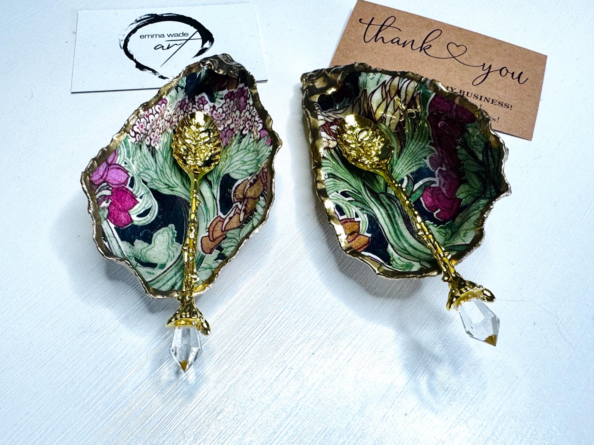 Handcrafted pair of oyster shell salt and pepper pinch pots featuring the Forest Trees botanical design in rich green, pink, cream and gold tones. Natural Dorset oyster shells hand-finished with liquid gold leaf edging and sealed beneath a crystal-clear resin for a glossy finish. Includes optional gold crystal spoons. Elegant table decor for dining, entertaining, weddings, anniversaries and housewarming gifts. Handmade in Surrey, England by Emma Wade ART.