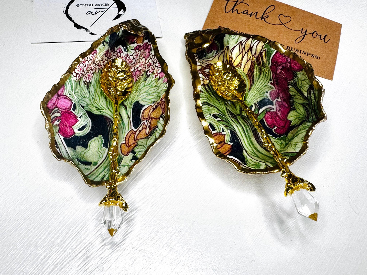 Handcrafted pair of oyster shell salt and pepper pinch pots featuring the Forest Trees botanical design in rich green, pink, cream and gold tones. Natural Dorset oyster shells hand-finished with liquid gold leaf edging and sealed beneath a crystal-clear resin for a glossy finish. Includes optional gold crystal spoons. Elegant table decor for dining, entertaining, weddings, anniversaries and housewarming gifts. Handmade in Surrey, England by Emma Wade ART.