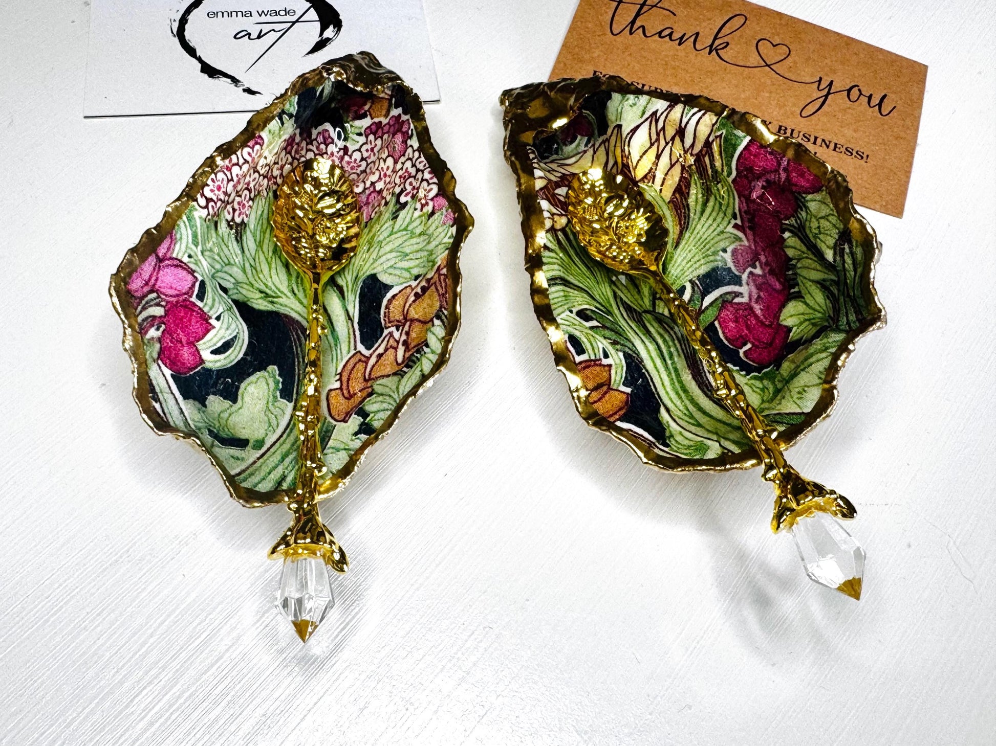 Handcrafted pair of oyster shell salt and pepper pinch pots featuring the Forest Trees botanical design in rich green, pink, cream and gold tones. Natural Dorset oyster shells hand-finished with liquid gold leaf edging and sealed beneath a crystal-clear resin for a glossy finish. Includes optional gold crystal spoons. Elegant table decor for dining, entertaining, weddings, anniversaries and housewarming gifts. Handmade in Surrey, England by Emma Wade ART.
