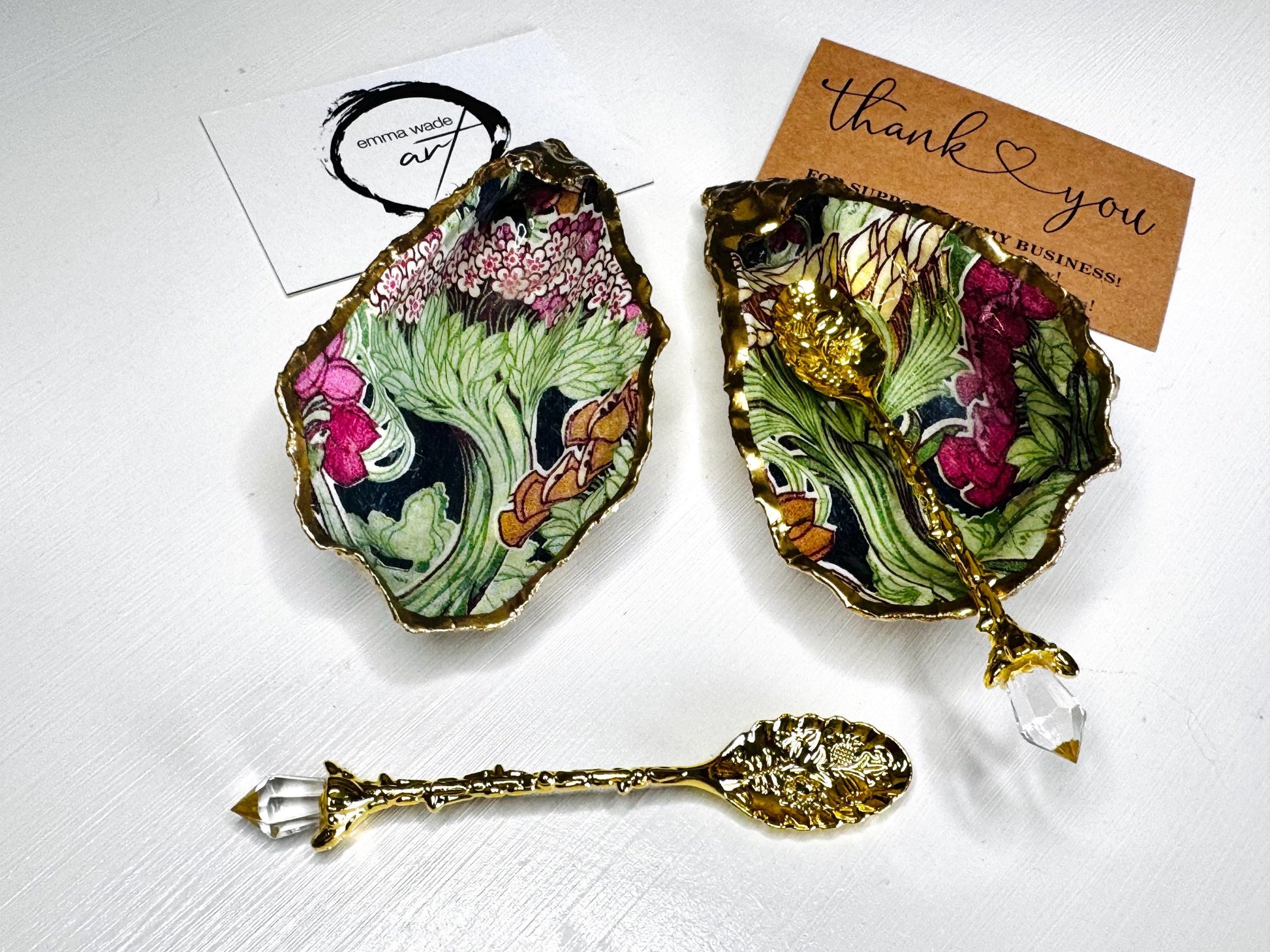 Handcrafted pair of oyster shell salt and pepper pinch pots featuring the Forest Trees botanical design in rich green, pink, cream and gold tones. Natural Dorset oyster shells hand-finished with liquid gold leaf edging and sealed beneath a crystal-clear resin for a glossy finish. Includes optional gold crystal spoons. Elegant table decor for dining, entertaining, weddings, anniversaries and housewarming gifts. Handmade in Surrey, England by Emma Wade ART.