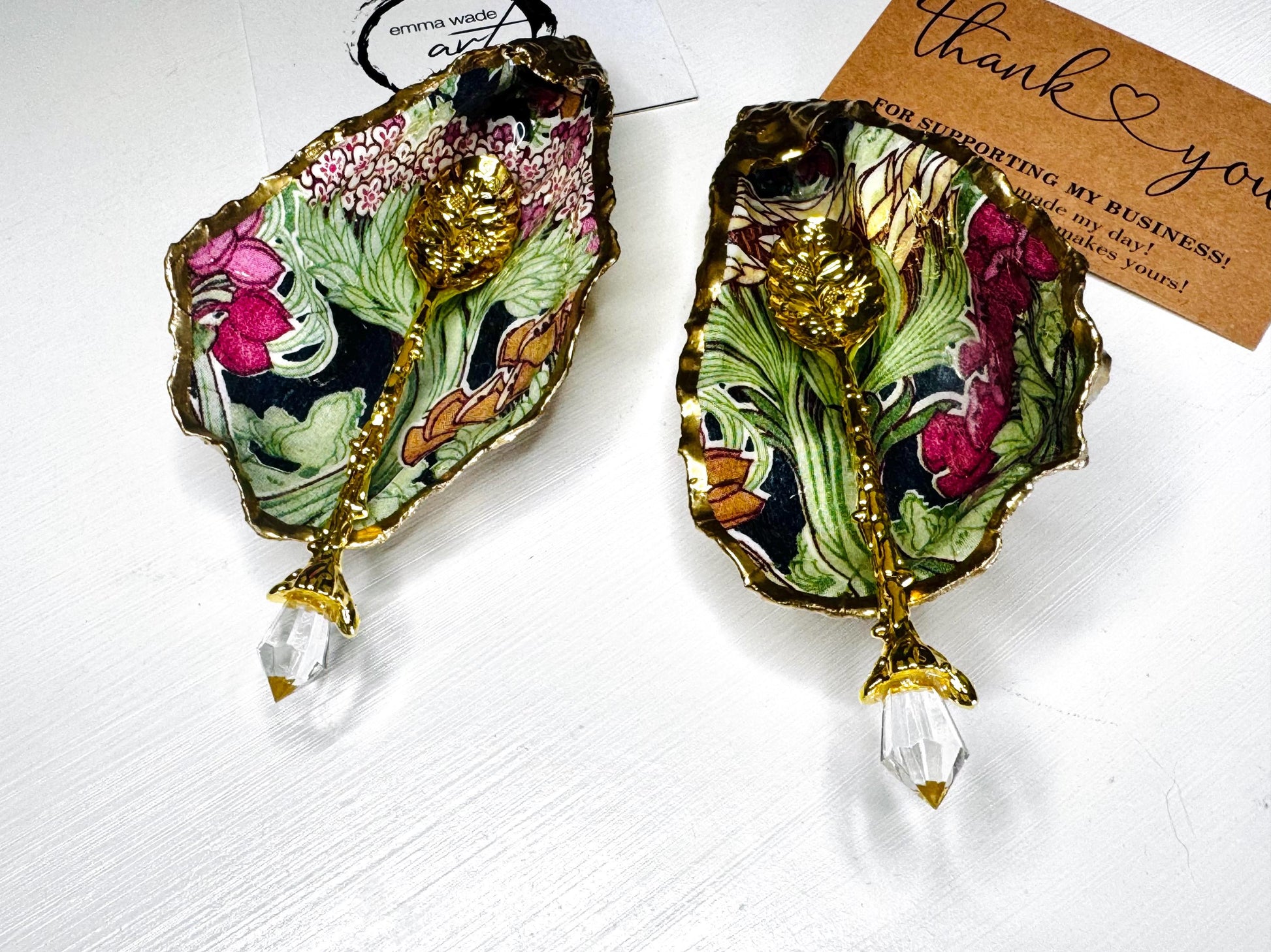 Handcrafted pair of oyster shell salt and pepper pinch pots featuring the Forest Trees botanical design in rich green, pink, cream and gold tones. Natural Dorset oyster shells hand-finished with liquid gold leaf edging and sealed beneath a crystal-clear resin for a glossy finish. Includes optional gold crystal spoons. Elegant table decor for dining, entertaining, weddings, anniversaries and housewarming gifts. Handmade in Surrey, England by Emma Wade ART.
