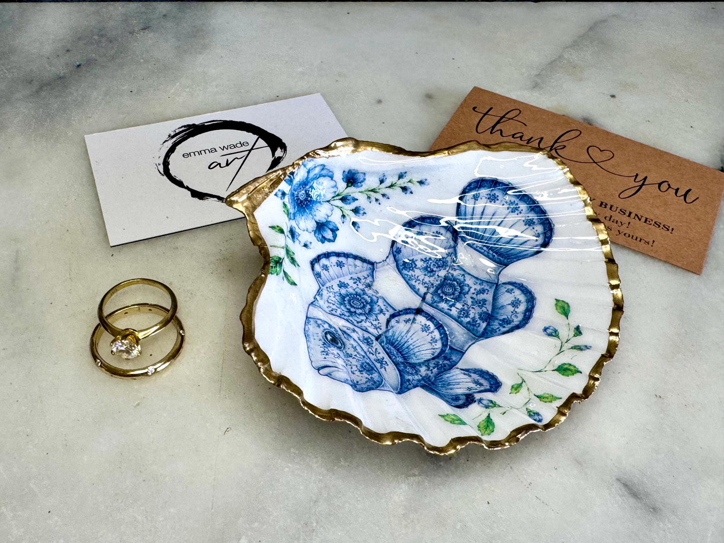 Clownfish scallop shell trinket dish featuring an original illustrated Delft Blue design by Emma Wade ART. Natural scallop shell finished with gold leaf or silver leaf edging and a crystal-clear glossy resin coating. Coastal jewellery tray, ring holder and ocean-inspired gift for fish and sea lovers, beach house décor, weddings, bridesmaids and nautical homes.