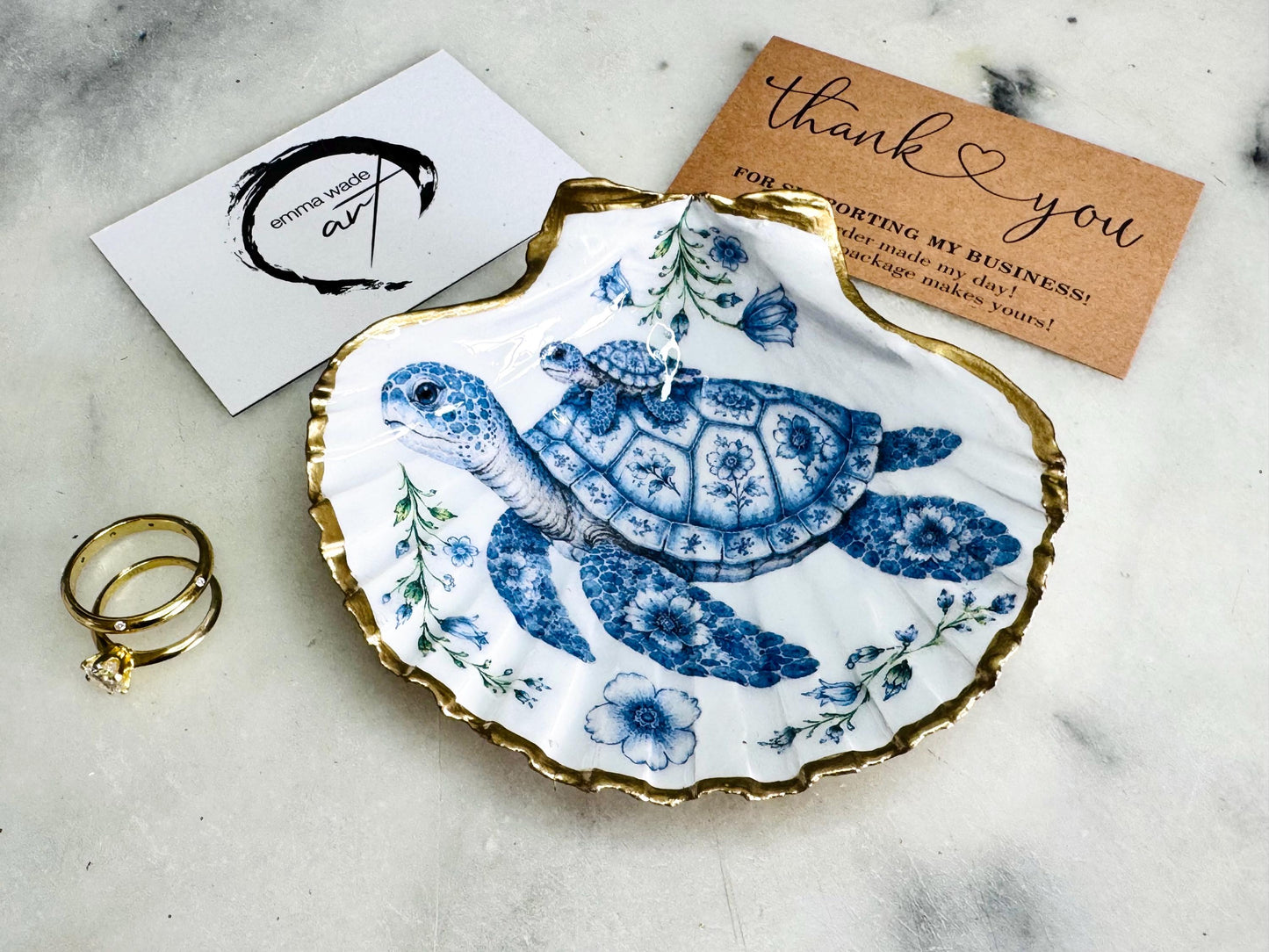 Sea Turtle Mum and Baby scallop shell trinket dish featuring an original illustrated Delft Blue design by Emma Wade ART. Natural scallop shell finished with gold leaf or silver leaf edging and a crystal-clear glossy resin coating. Coastal jewellery tray, ring holder and ocean-inspired gift for sea turtle lovers, beach house décor, weddings, bridesmaids and nautical homes.