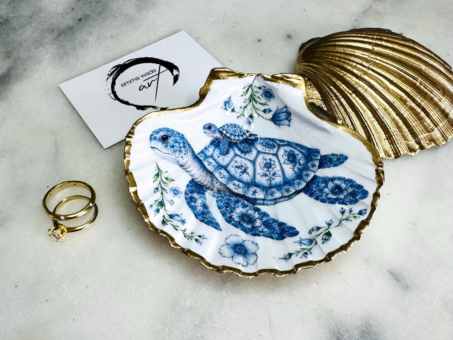 Sea Turtle Mum and Baby scallop shell trinket dish featuring an original illustrated Delft Blue design by Emma Wade ART. Natural scallop shell finished with gold leaf or silver leaf edging and a crystal-clear glossy resin coating. Coastal jewellery tray, ring holder and ocean-inspired gift for sea turtle lovers, beach house décor, weddings, bridesmaids and nautical homes.