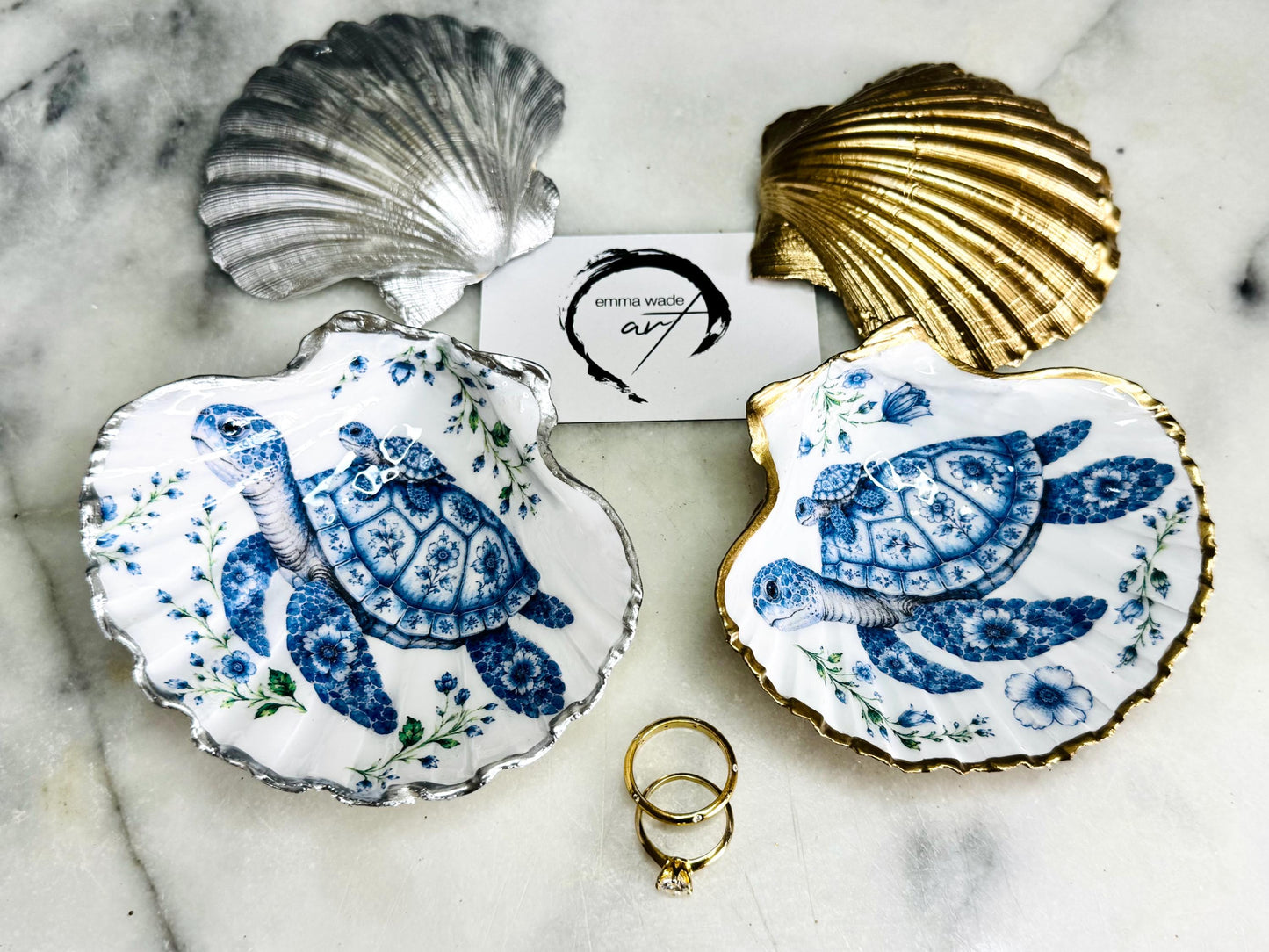 Sea Turtle Mum and Baby scallop shell trinket dish featuring an original illustrated Delft Blue design by Emma Wade ART. Natural scallop shell finished with gold leaf or silver leaf edging and a crystal-clear glossy resin coating. Coastal jewellery tray, ring holder and ocean-inspired gift for sea turtle lovers, beach house décor, weddings, bridesmaids and nautical homes.