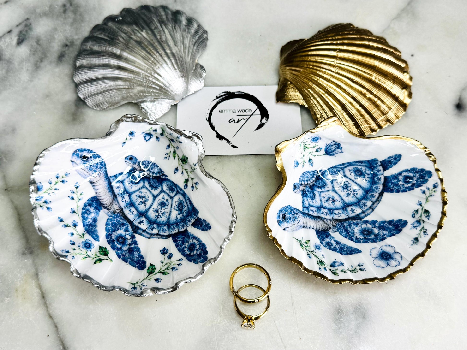 Sea Turtle Mum and Baby scallop shell trinket dish featuring an original illustrated Delft Blue design by Emma Wade ART. Natural scallop shell finished with gold leaf or silver leaf edging and a crystal-clear glossy resin coating. Coastal jewellery tray, ring holder and ocean-inspired gift for sea turtle lovers, beach house décor, weddings, bridesmaids and nautical homes.
