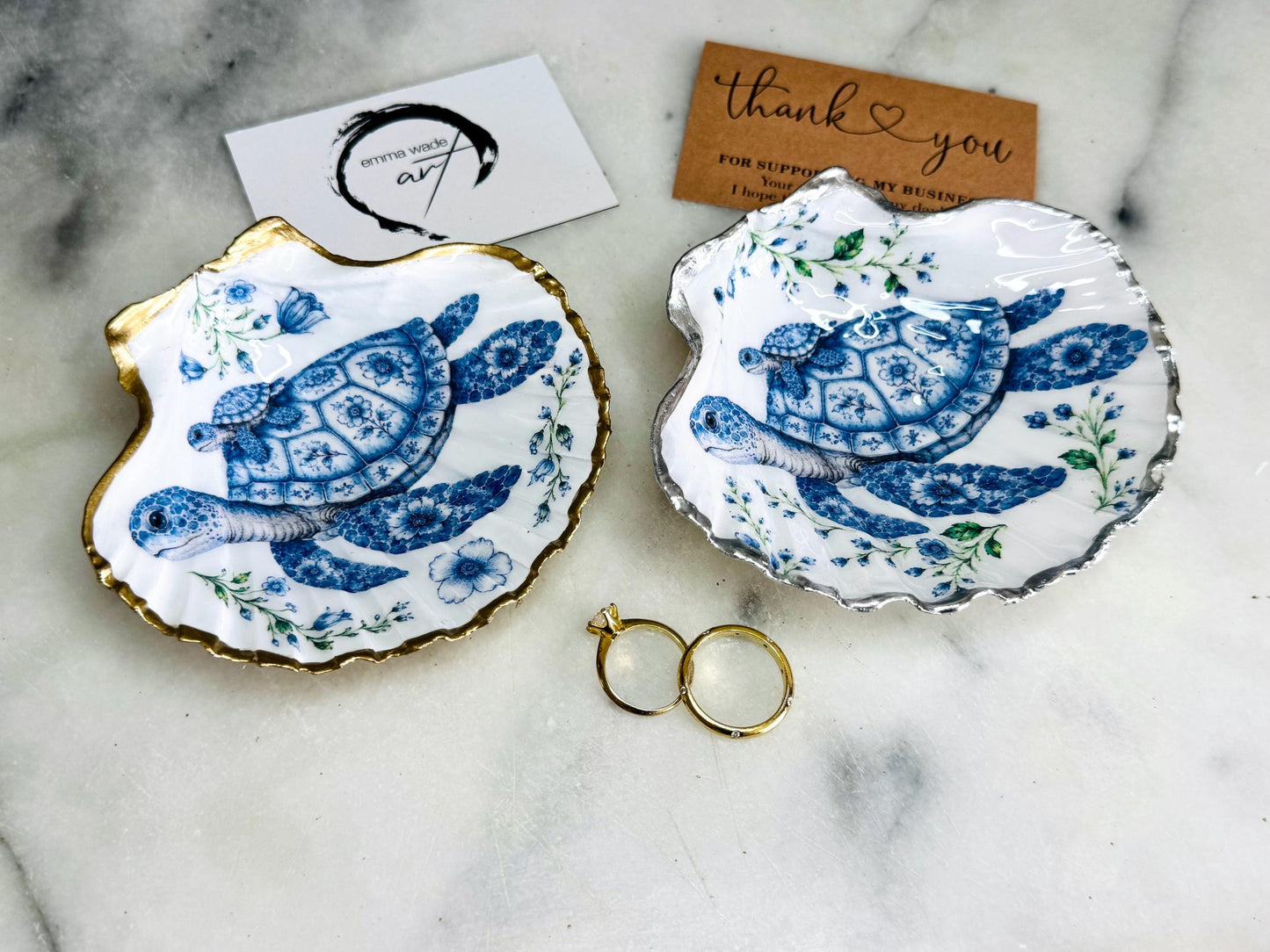 Sea Turtle Mum and Baby scallop shell trinket dish featuring an original illustrated Delft Blue design by Emma Wade ART. Natural scallop shell finished with gold leaf or silver leaf edging and a crystal-clear glossy resin coating. Coastal jewellery tray, ring holder and ocean-inspired gift for sea turtle lovers, beach house décor, weddings, bridesmaids and nautical homes.