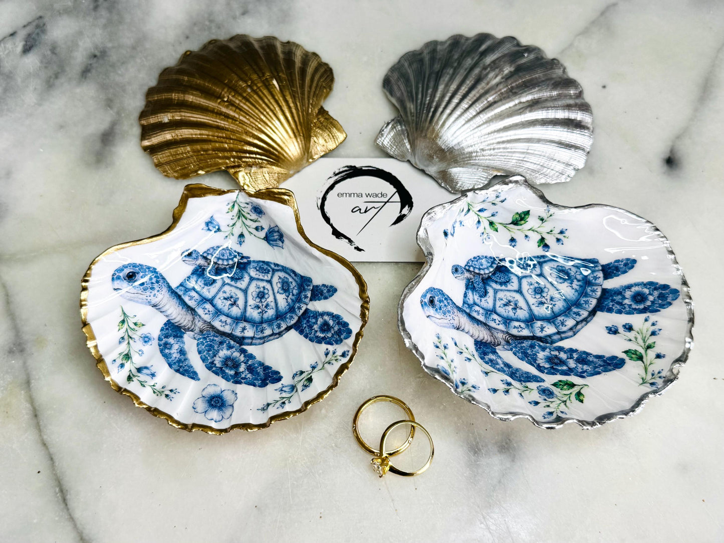 Sea Turtle Mum and Baby scallop shell trinket dish featuring an original illustrated Delft Blue design by Emma Wade ART. Natural scallop shell finished with gold leaf or silver leaf edging and a crystal-clear glossy resin coating. Coastal jewellery tray, ring holder and ocean-inspired gift for sea turtle lovers, beach house décor, weddings, bridesmaids and nautical homes.
