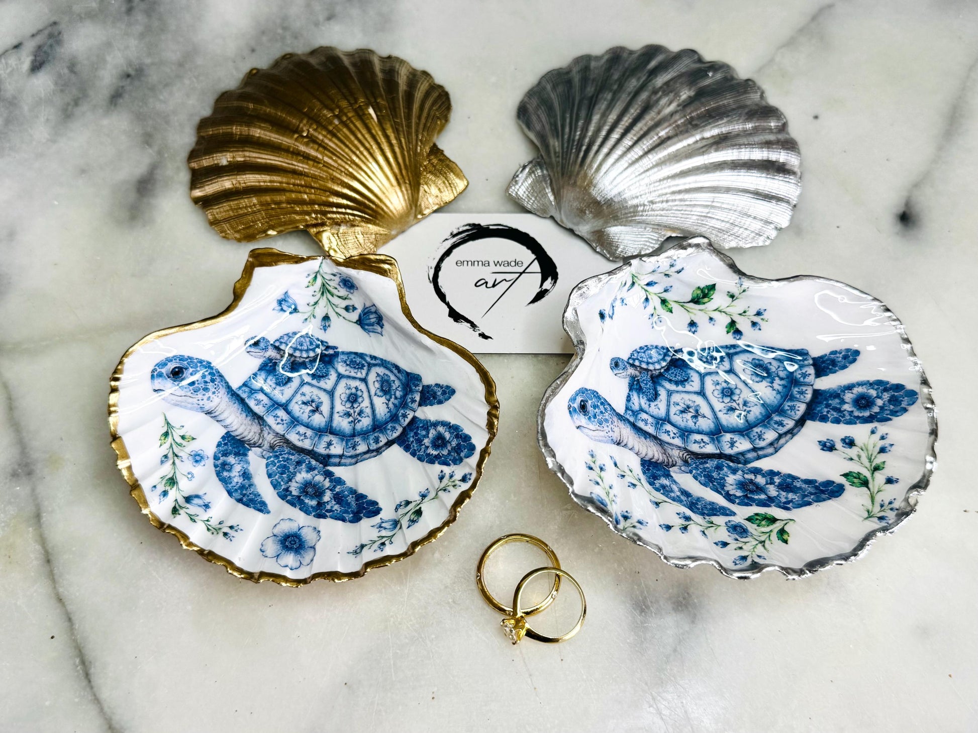 Sea Turtle Mum and Baby scallop shell trinket dish featuring an original illustrated Delft Blue design by Emma Wade ART. Natural scallop shell finished with gold leaf or silver leaf edging and a crystal-clear glossy resin coating. Coastal jewellery tray, ring holder and ocean-inspired gift for sea turtle lovers, beach house décor, weddings, bridesmaids and nautical homes.