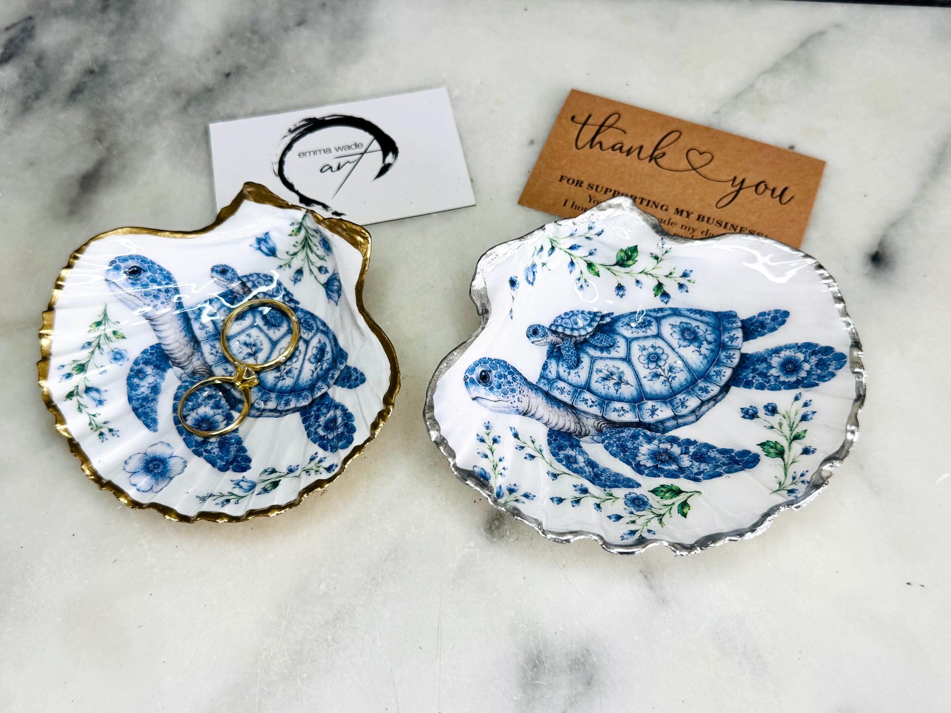 Sea Turtle Mum and Baby scallop shell trinket dish featuring an original illustrated Delft Blue design by Emma Wade ART. Natural scallop shell finished with gold leaf or silver leaf edging and a crystal-clear glossy resin coating. Coastal jewellery tray, ring holder and ocean-inspired gift for sea turtle lovers, beach house décor, weddings, bridesmaids and nautical homes.