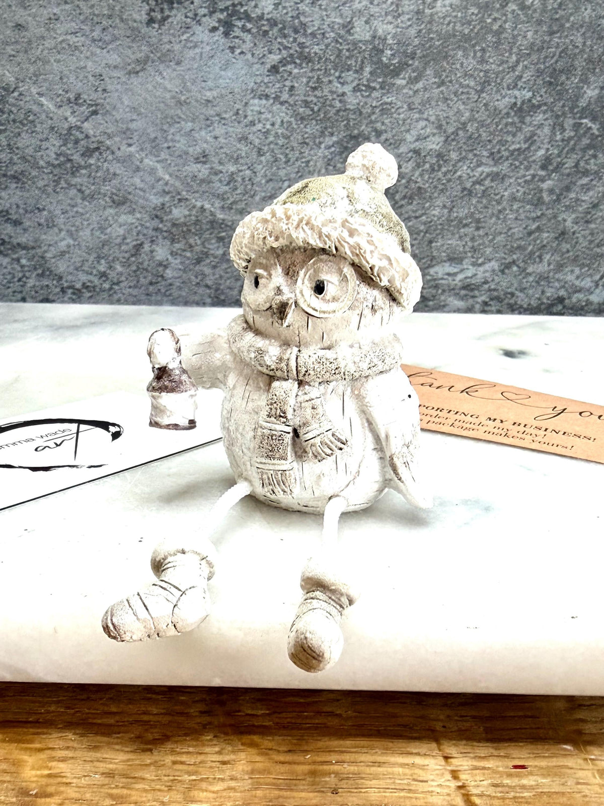 Set of three woodland Christmas owl shelf sitter decorations in soft white, grey and natural tones, featuring winter hats, scarves and festive details. Moulded resin owl ornaments with subtle glitter accents and dangling cord legs with little boots, designed to sit on a shelf, mantelpiece or windowsill. Festive woodland Christmas décor and owl lover gift.