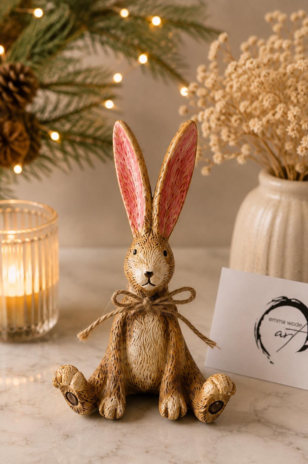 Hand finished brown Christmas rabbit ornament with soft pink inner ears and a rustic jute bow. Single resin bunny decoration sold individually, styled as festive shelf decor for a mantelpiece, console table or woodland Christmas display. Rustic country home ornament and Christmas gift for rabbit lovers.