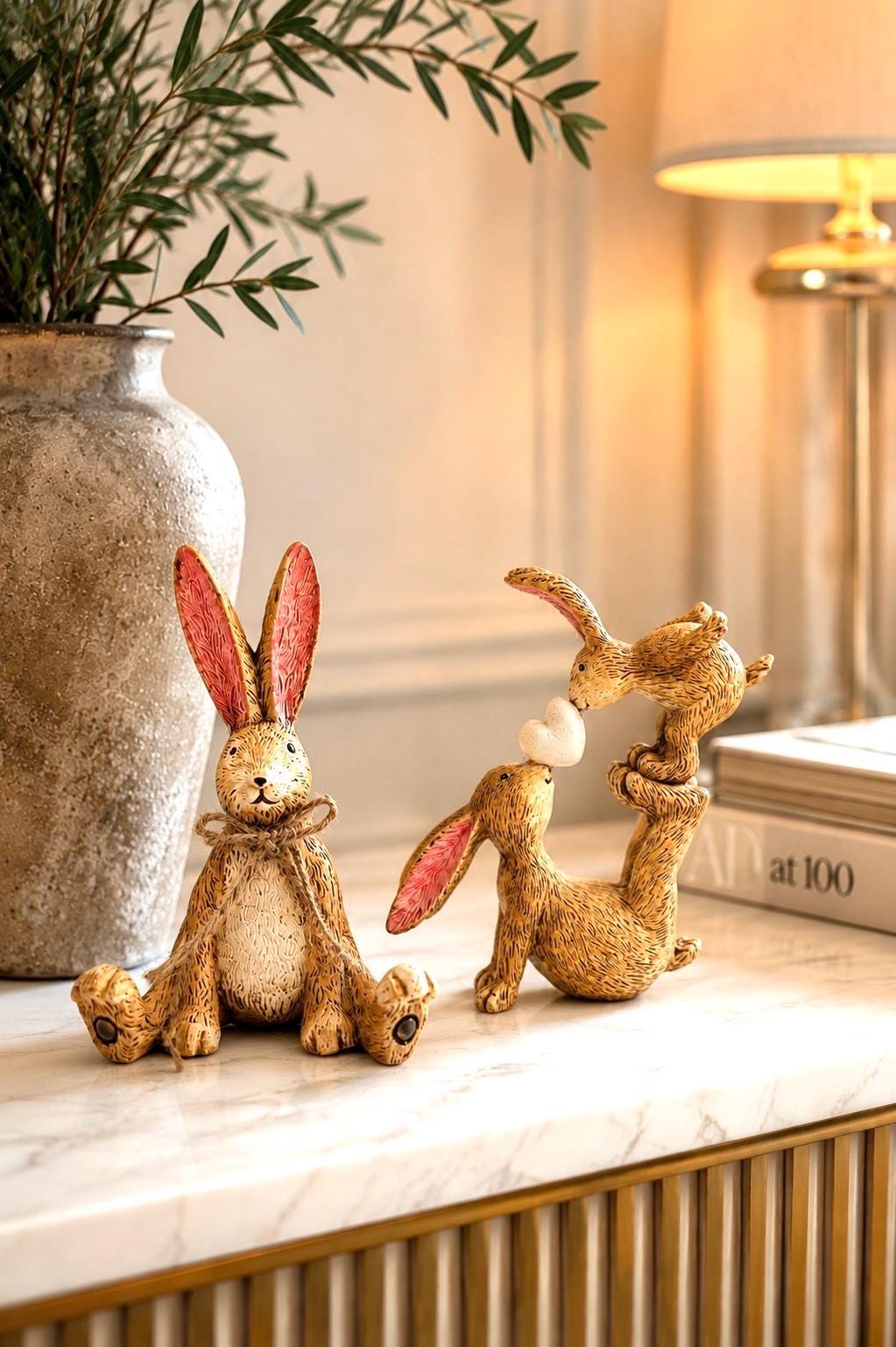Hand finished polyresin Christmas bunny ornaments with rustic jute bows and soft pink inner ears. Decorative rabbit shelf ornaments shown as a seated bunny and two bunnies kissing, available individually or as a set. Festive woodland-style decor for Christmas shelves, mantelpieces, cottage interiors and rabbit lover gifts.
