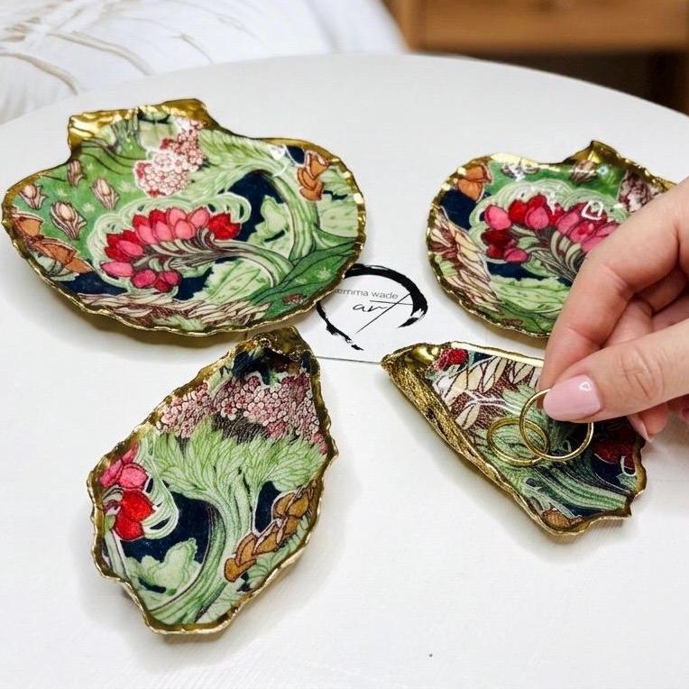 Handcrafted V&A Museum Swirling Trees shell dish collection featuring large and small scallop shells and oyster shells decorated with flowing botanical artwork, pink water lilies and rich green foliage. Each natural Dorset shell is hand-gilded with real liquid gold leaf and sealed with crystal-clear resin. Luxury coastal decor, jewellery dishes, ring holders and trinket trays. Available individually or as a coordinated set of four shells.