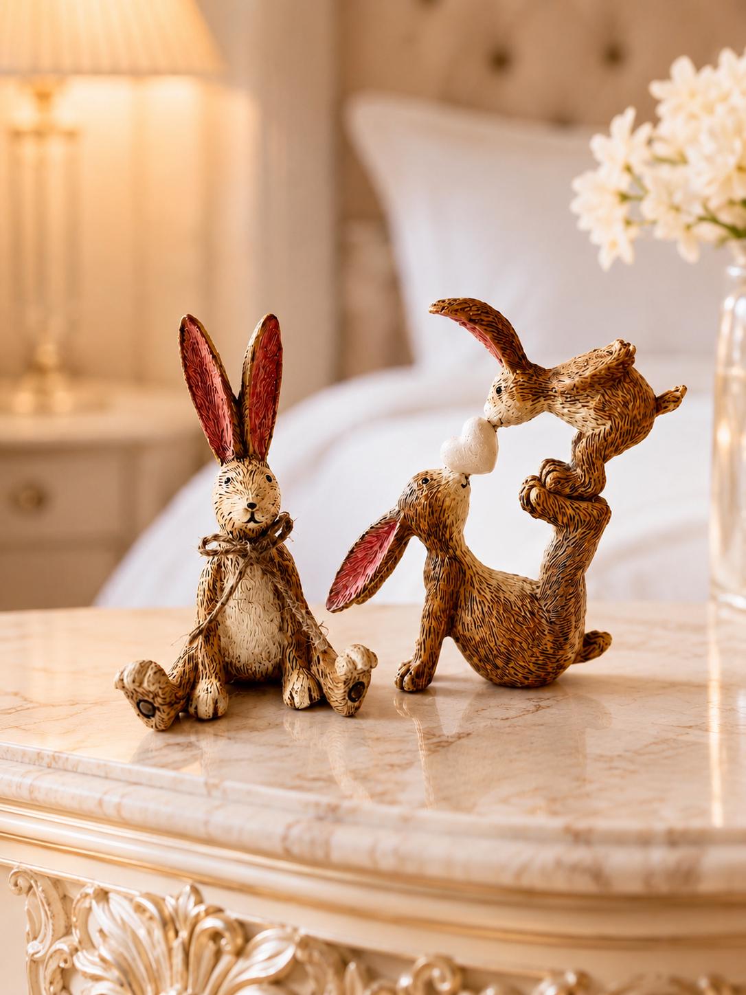 Hand finished polyresin Christmas bunny ornaments with rustic jute bows and soft pink inner ears. Decorative rabbit shelf ornaments shown as a seated bunny and two bunnies kissing, available individually or as a set. Festive woodland-style decor for Christmas shelves, mantelpieces, cottage interiors and rabbit lover gifts.