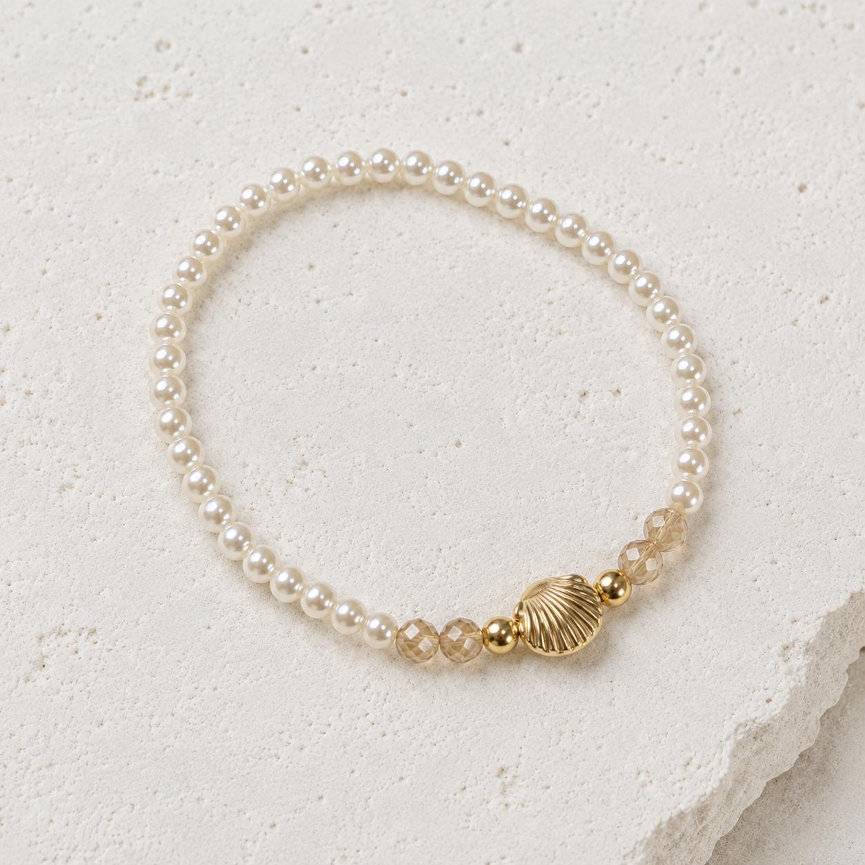 Set of three delicate coastal stretch bracelets featuring small ivory faux pearls and gold-tone seaside details. The coordinating jewellery set includes a blush enamel-style scallop shell charm with pearl centre, a textured gold starfish charm and a ridged gold shell centrepiece with pale champagne faceted beads. Lightweight 16 cm elasticated bohemian costume jewellery for coastal gifts, Christmas presents, stocking fillers, holidays, beach weddings, bridesmaids and gifts for her.