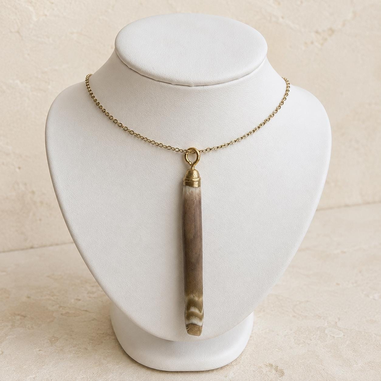 Handmade natural sea-urchin spine necklace displayed on a white jewellery bust with liquid gold leaf at both ends and an 18-inch 18K gold-plated chain.