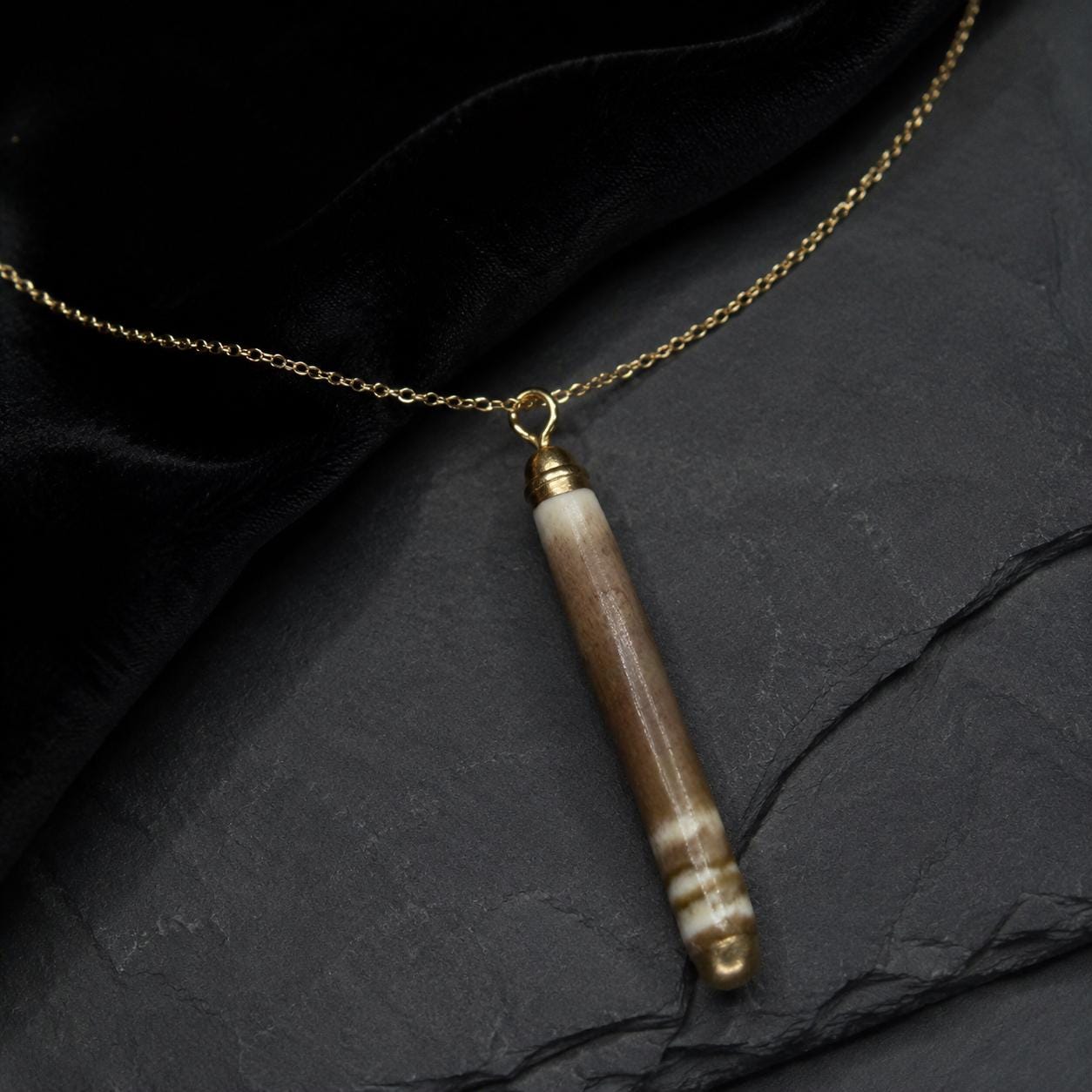 Handmade pencil-urchin spine necklace arranged on a dark luxury background with an 18K gold-plated chain and liquid-gold detail