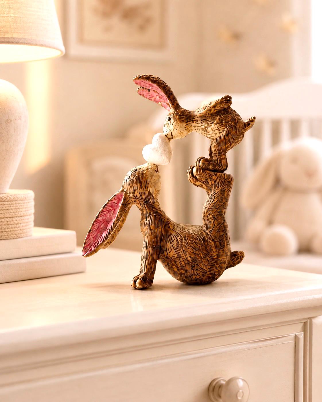 Hand finished brown polyresin bunny and baby rabbit ornament, showing a larger rabbit balancing a baby bunny above with a white heart between them. Rustic textured rabbit figure with pink inner ears, suitable for Christmas shelf decor, mantel styling, rabbit lover gifts and year-round home decoration.