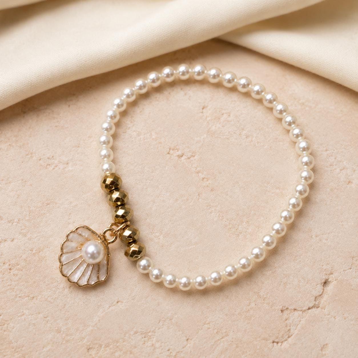 Set of three delicate coastal stretch bracelets featuring small ivory faux pearls and gold-tone seaside details. The coordinating jewellery set includes a blush enamel-style scallop shell charm with pearl centre, a textured gold starfish charm and a ridged gold shell centrepiece with pale champagne faceted beads. Lightweight 16 cm elasticated bohemian costume jewellery for coastal gifts, Christmas presents, stocking fillers, holidays, beach weddings, bridesmaids and gifts for her.