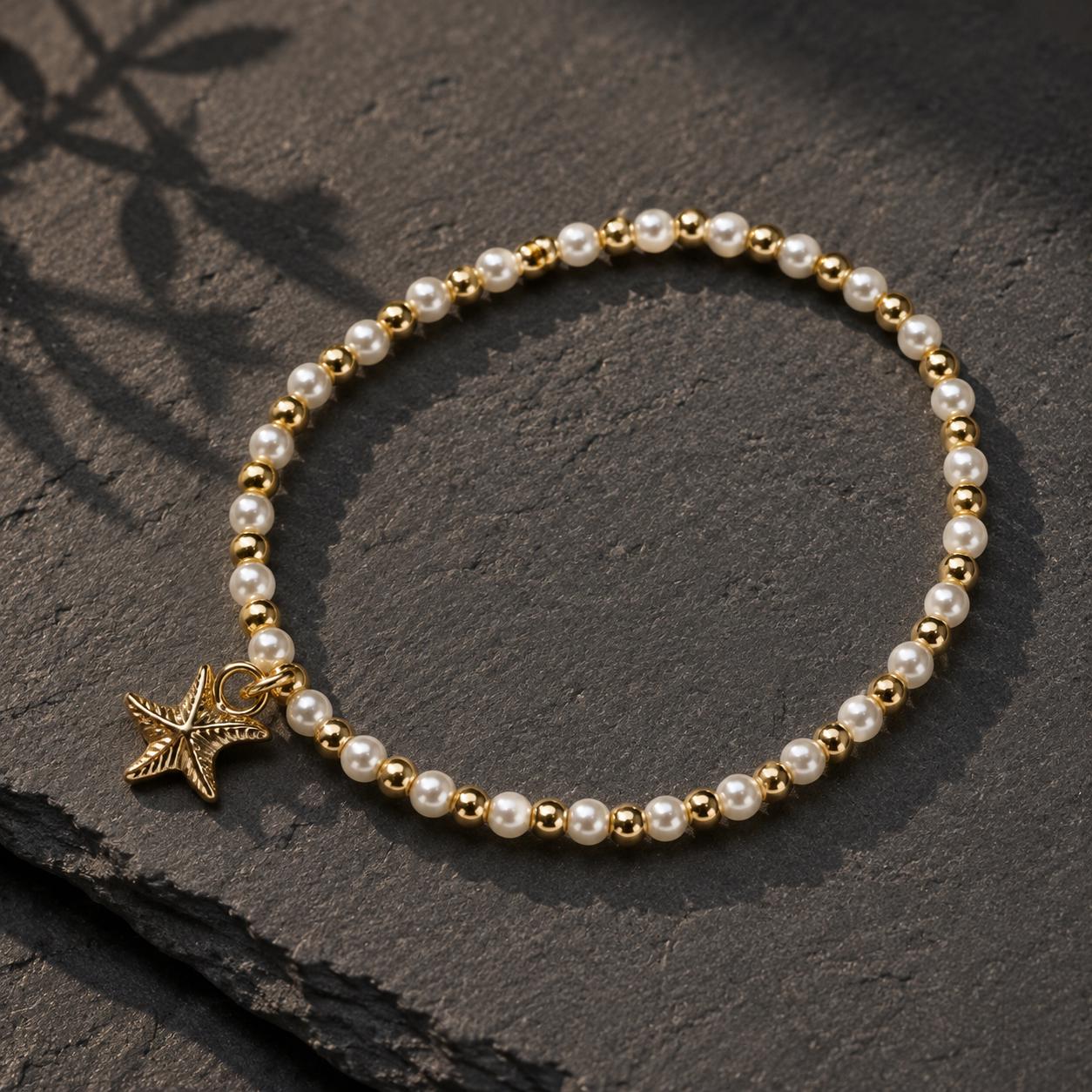 Set of three delicate coastal stretch bracelets featuring small ivory faux pearls and gold-tone seaside details. The coordinating jewellery set includes a blush enamel-style scallop shell charm with pearl centre, a textured gold starfish charm and a ridged gold shell centrepiece with pale champagne faceted beads. Lightweight 16 cm elasticated bohemian costume jewellery for coastal gifts, Christmas presents, stocking fillers, holidays, beach weddings, bridesmaids and gifts for her.