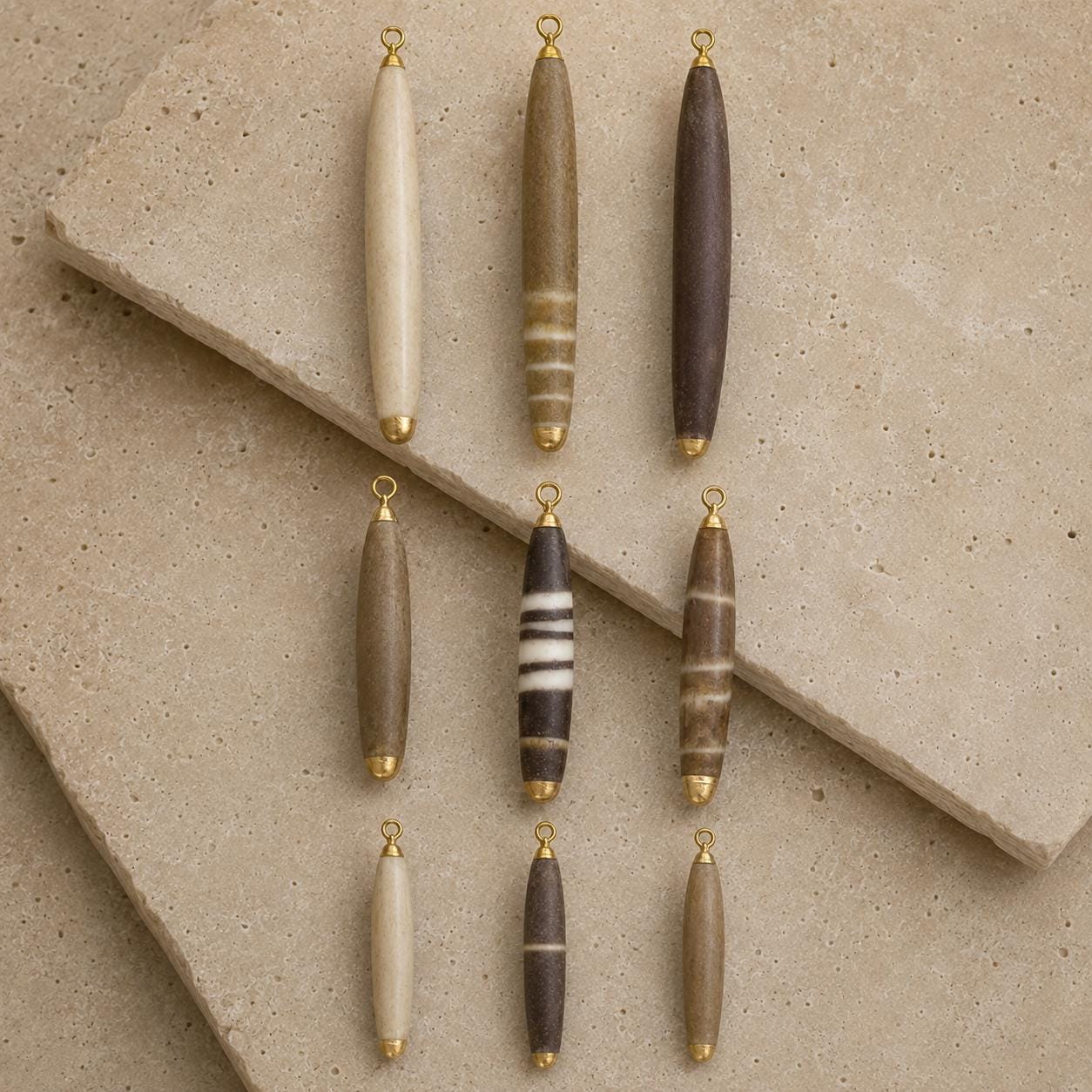 Nine individual pencil-urchin spine pendants arranged in three size groups, showing unique ivory, taupe, brown, plum and naturally banded markings.