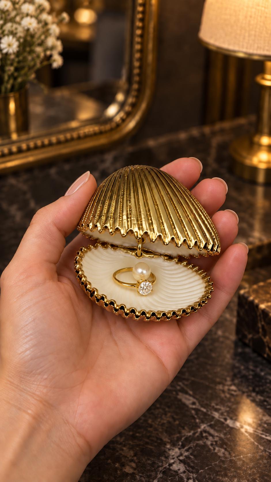 Handmade hinged cockle shell ring box with a natural white ridged interior and hand-finished gold-leaf edging. Available with a natural or gold-leaf outer shell, a natural or gold-speckled interior, and with no pearl or one pearl ring stop. A coastal jewellery box for storing rings and small treasured pieces.