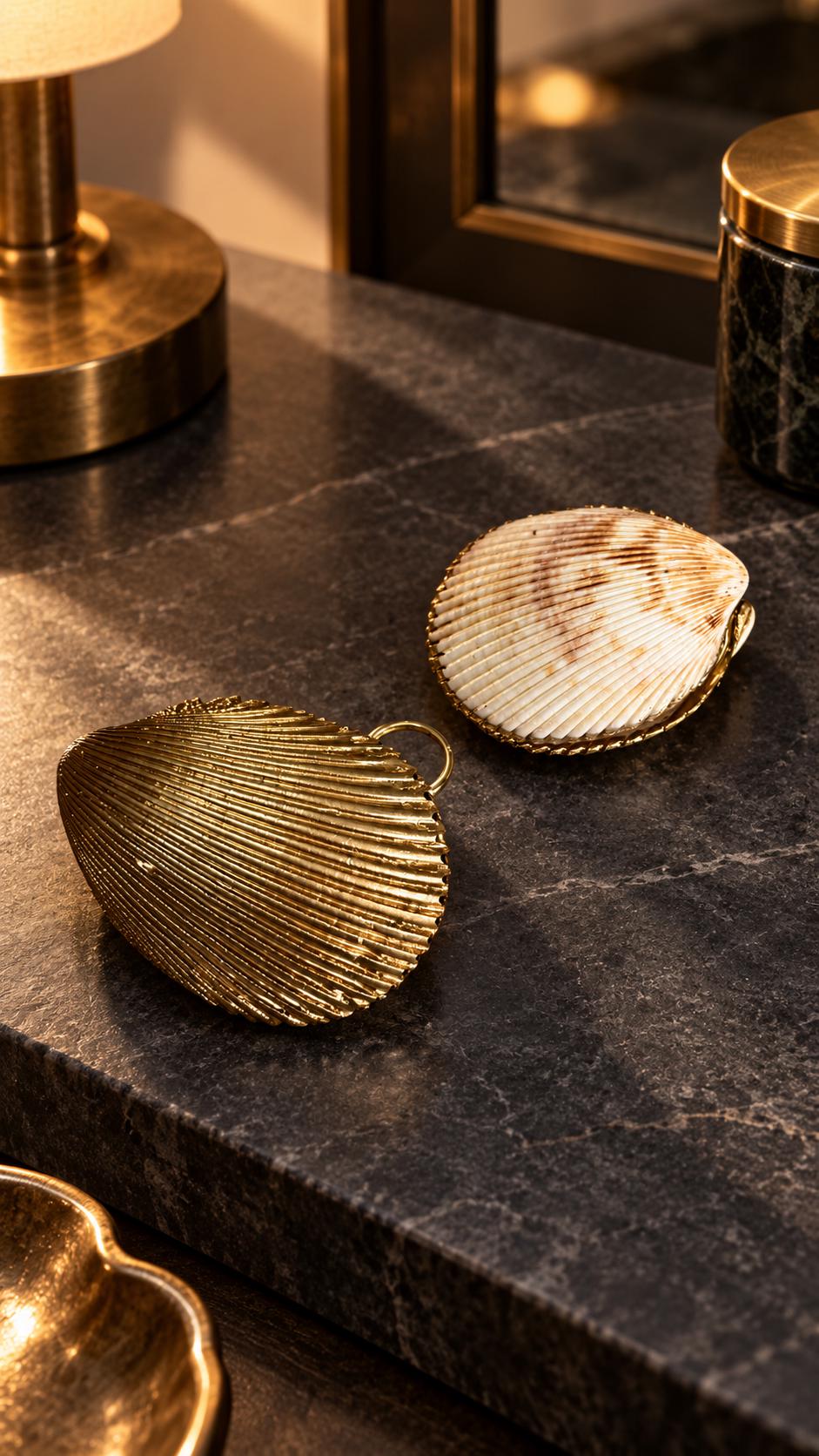 Handmade hinged cockle shell ring box with a natural white ridged interior and hand-finished gold-leaf edging. Available with a natural or gold-leaf outer shell, a natural or gold-speckled interior, and with no pearl or one pearl ring stop. A coastal jewellery box for storing rings and small treasured pieces.