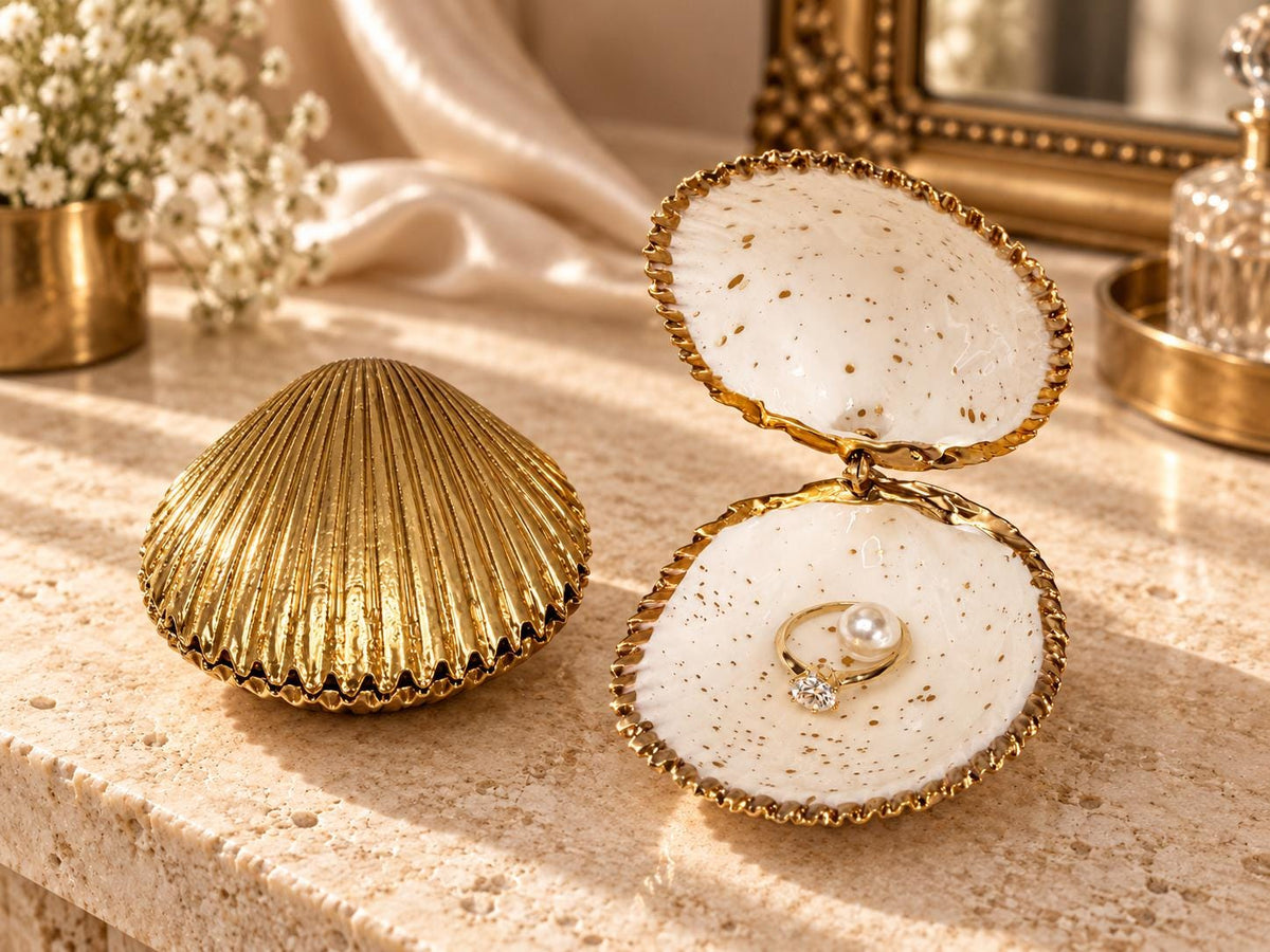 Handmade hinged cockle shell ring box with a natural white ridged interior and hand-finished gold-leaf edging. Available with a natural or gold-leaf outer shell, a natural or gold-speckled interior, and with no pearl or one pearl ring stop. A coastal jewellery box for storing rings and small treasured pieces.